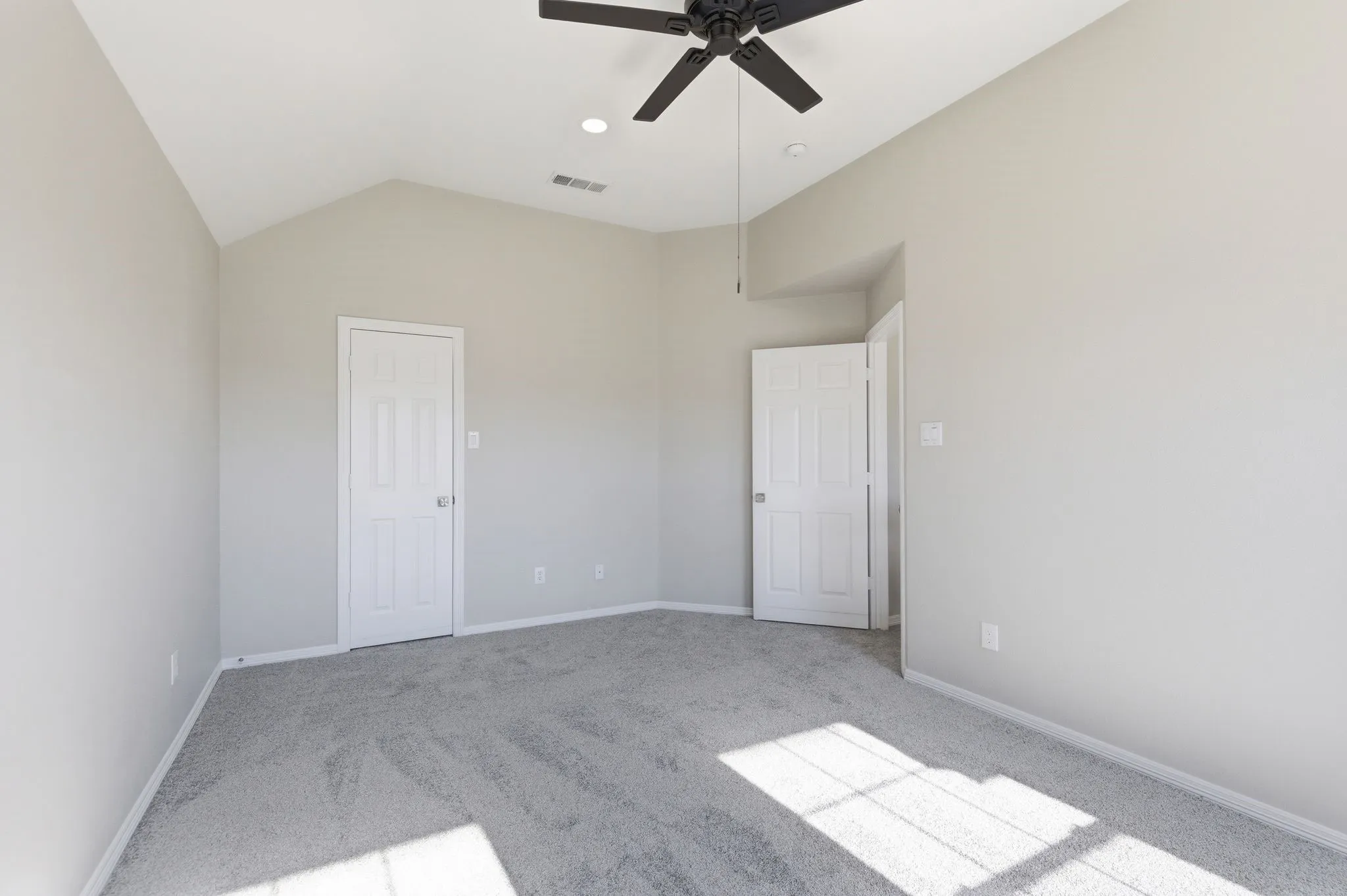 Vaulted ceiling room featuring light gray carpeting and neutral wall paint