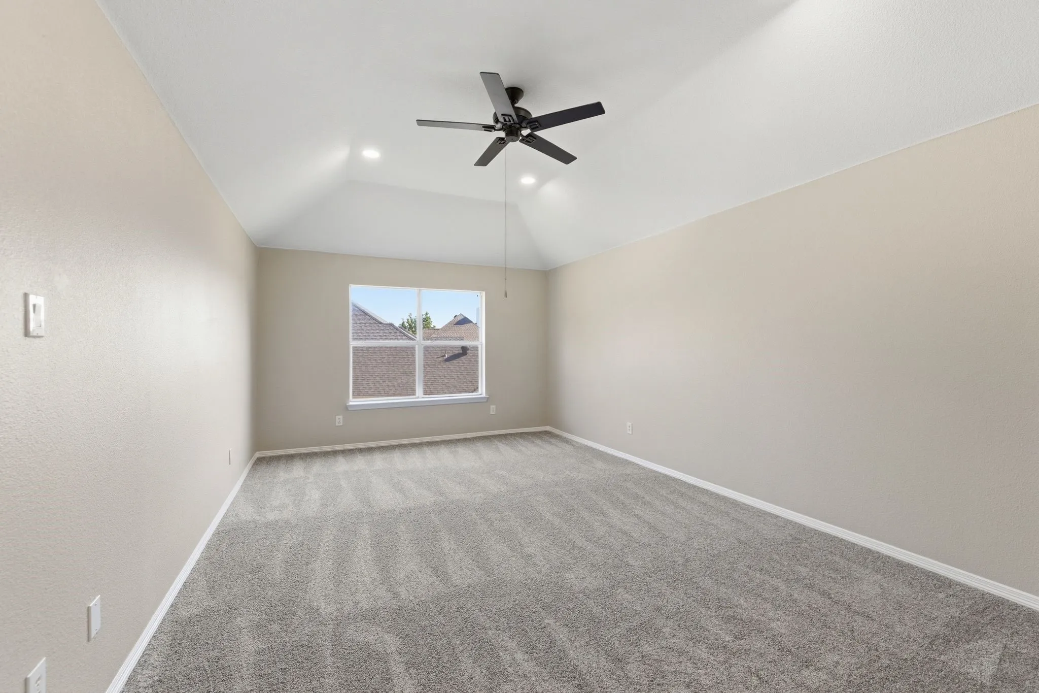 Spacious room featuring vaulted ceilings, recessed lighting, a ceiling fan, light gray carpeting, and a large window