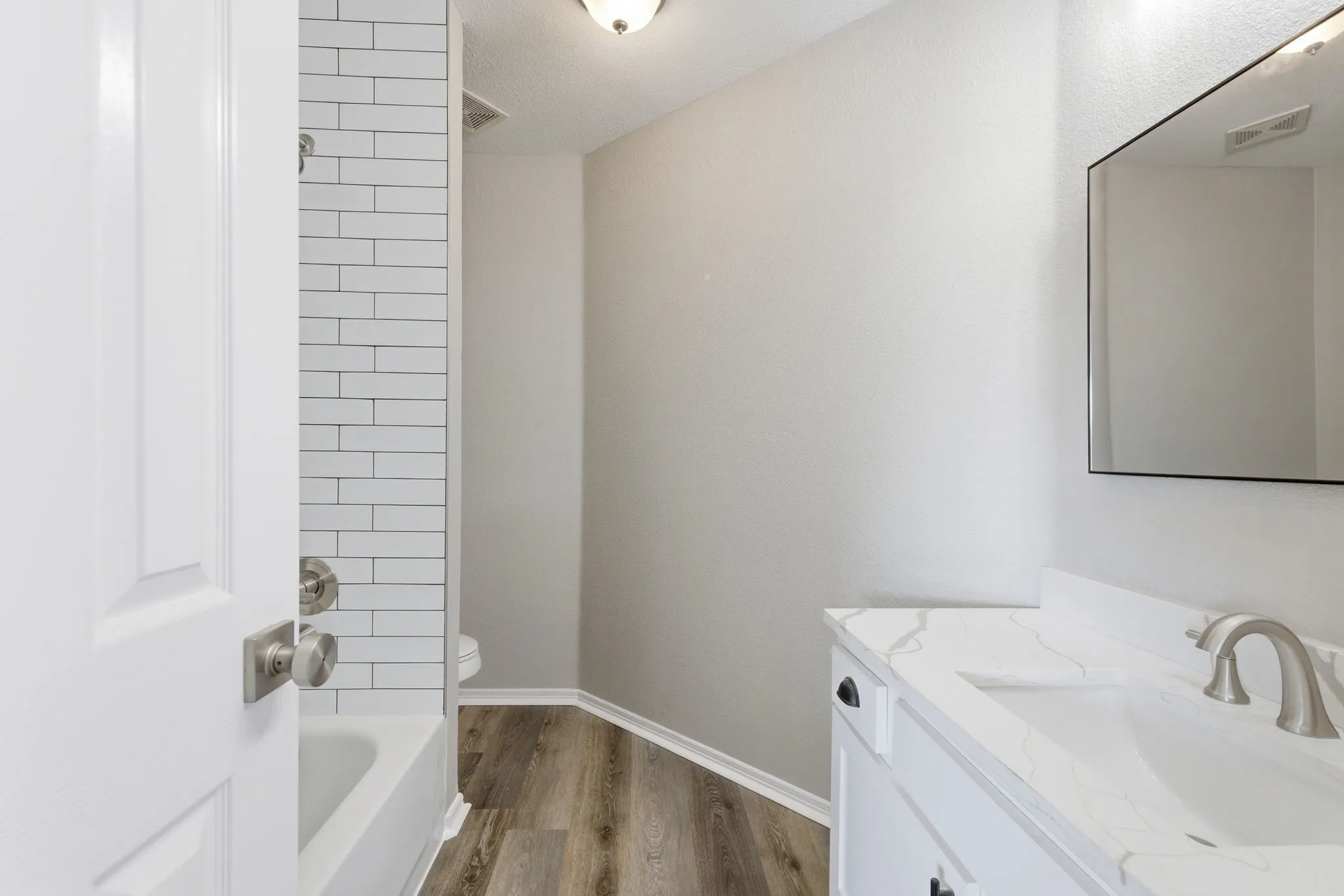 Bathroom featuring a white vanity with a stone-finish countertop, undermount sink, and brushed nickel faucet