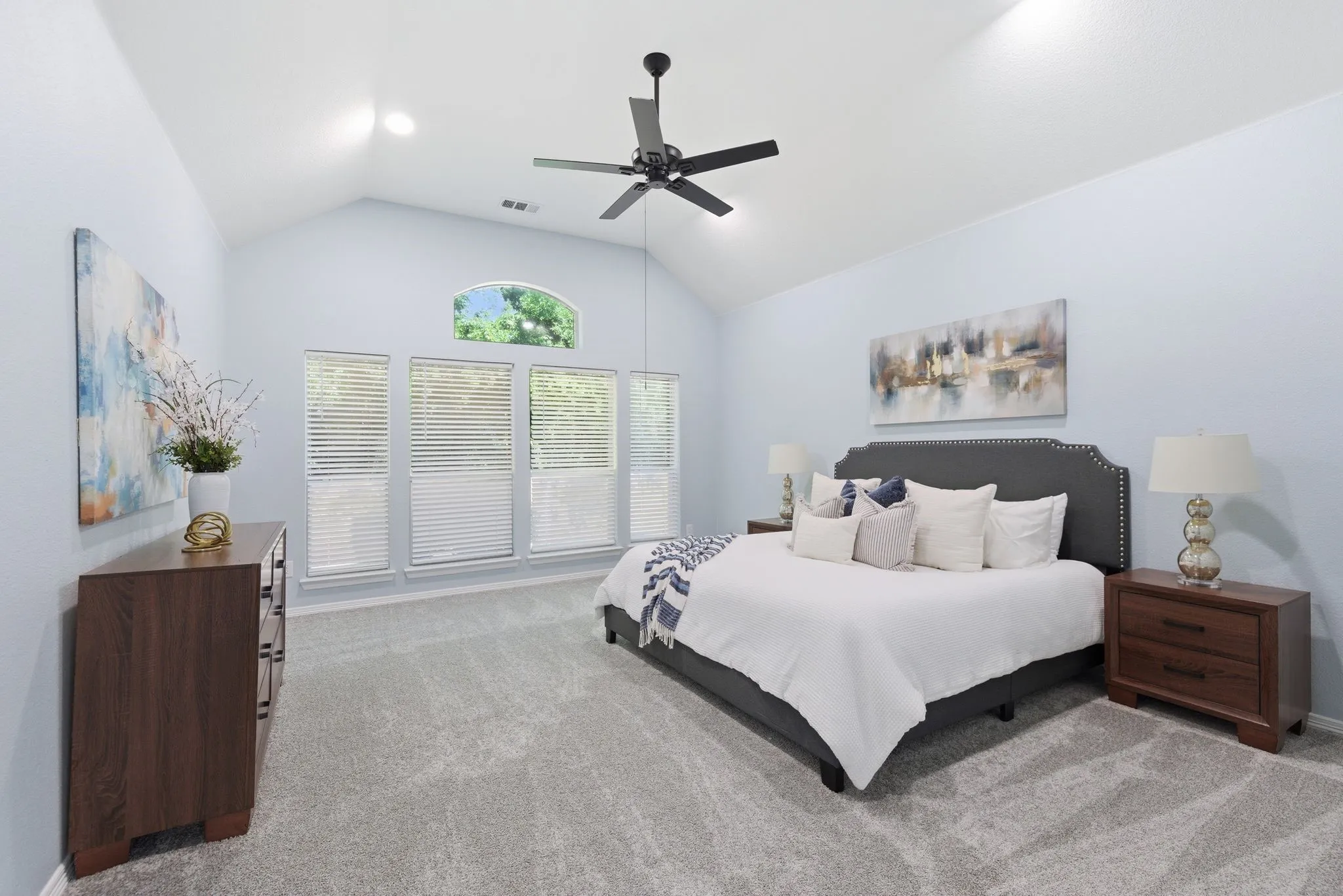Spacious room featuring vaulted ceilings, a contemporary ceiling fan, and light-colored carpeting