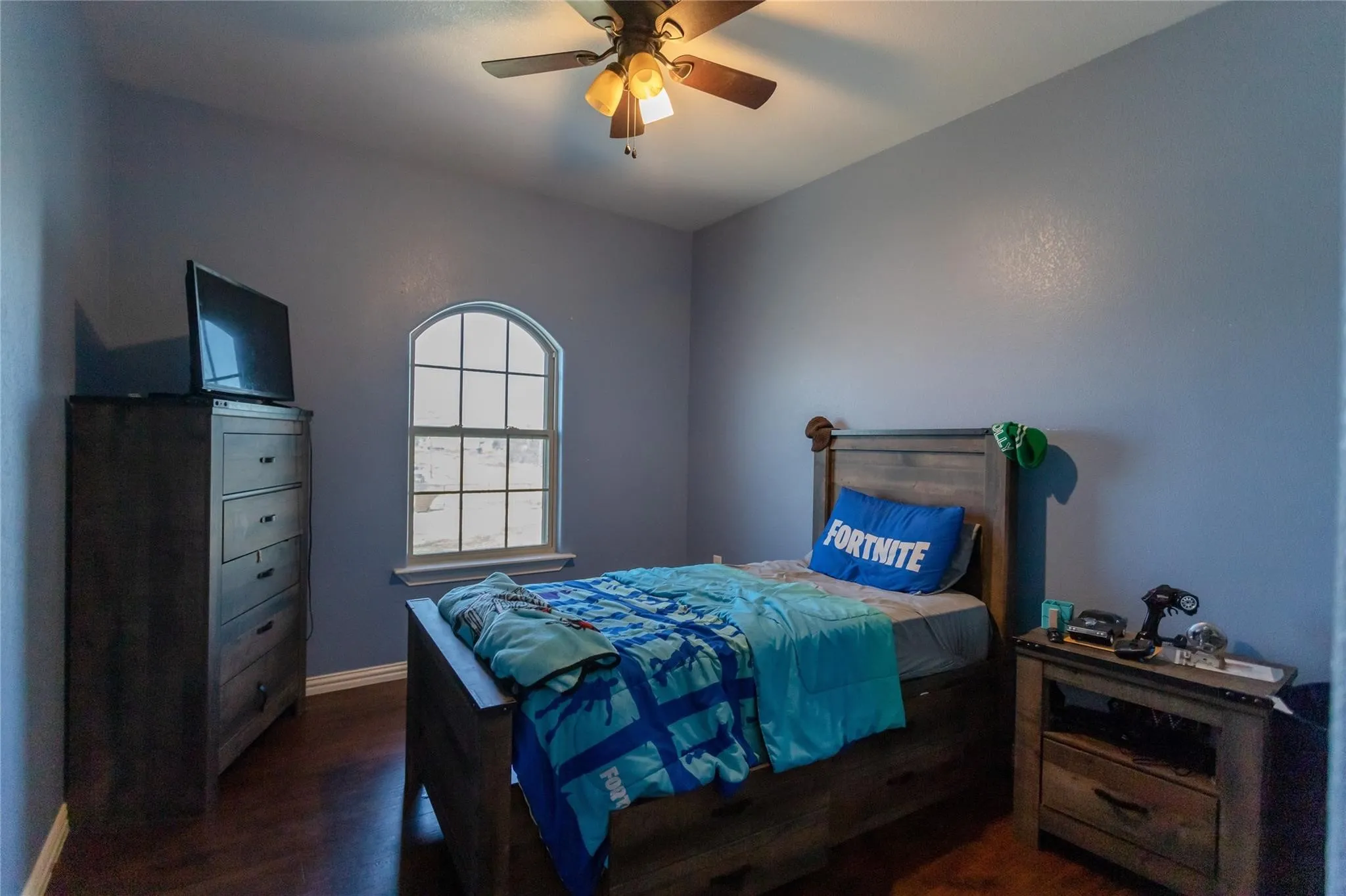 Arched window, wood-finish flooring, and a ceiling fan with integrated lighting