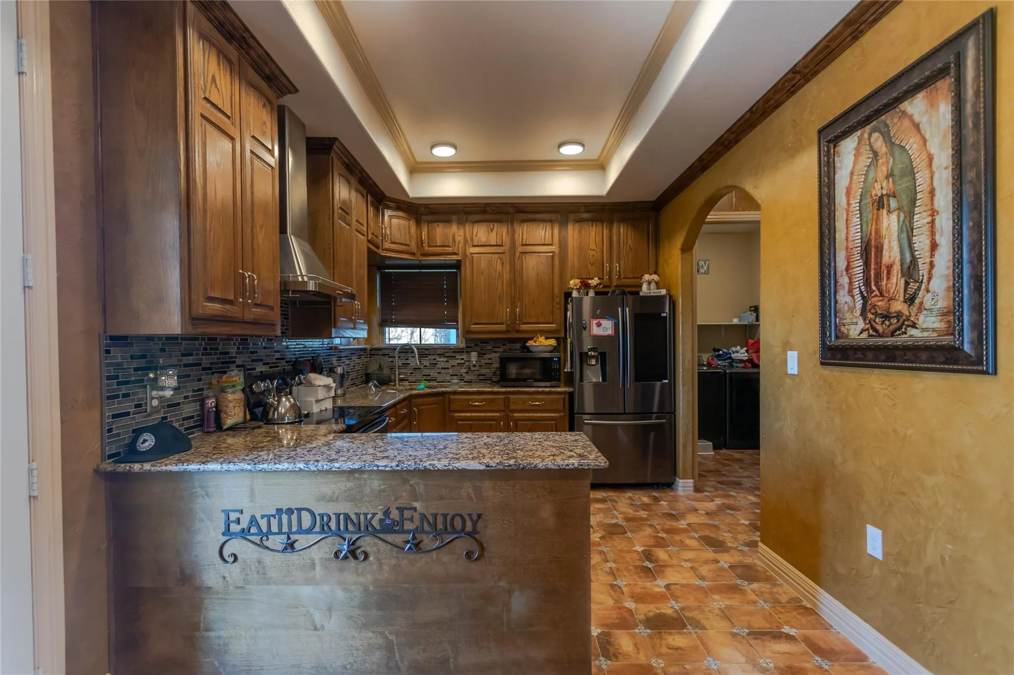 Wood-finish cabinetry, granite countertops, and a mosaic tile backsplash