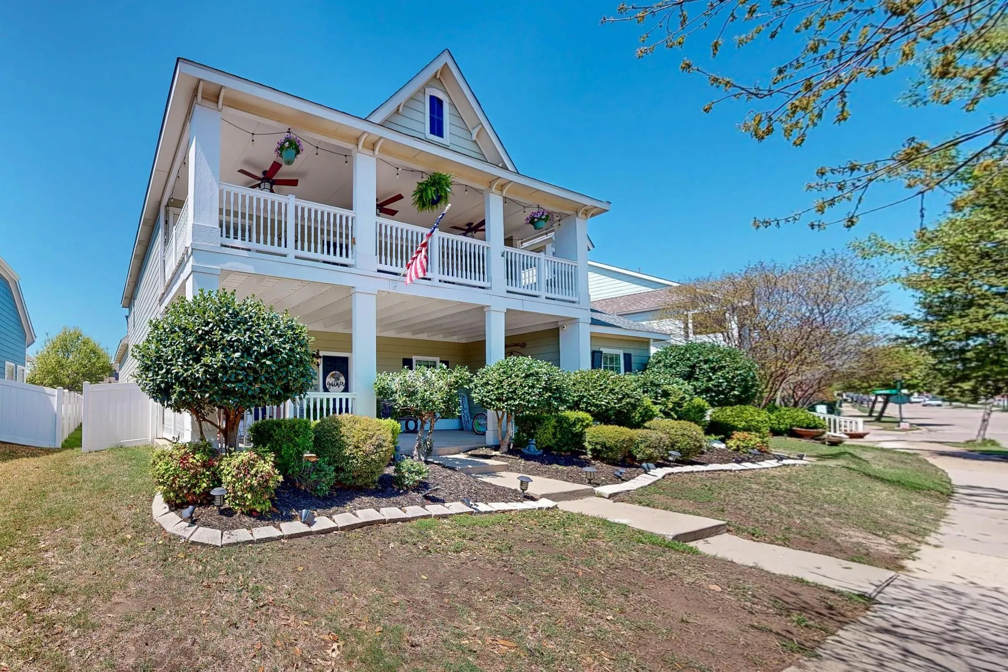 Two-story exterior with dual covered porches, gabled roofline, and established front landscaping