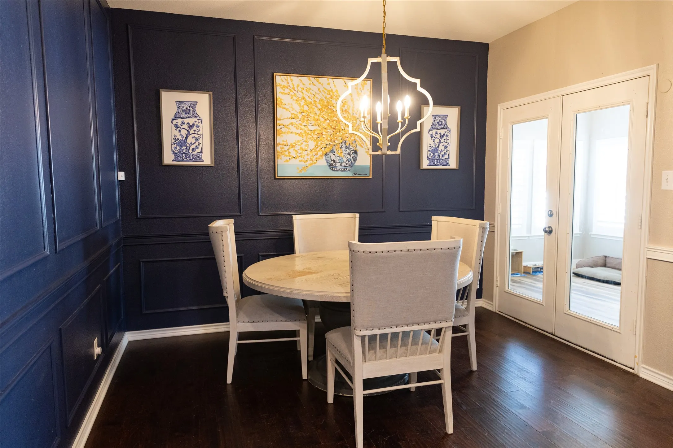 Wainscoting paneling, dark wood-finish flooring, and a decorative chandelier
