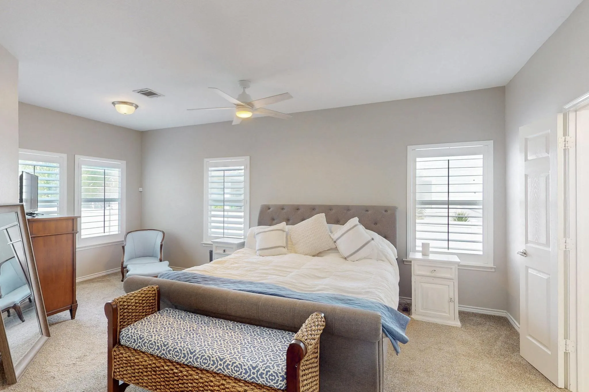 Carpeted room featuring multiple windows with plantation shutters, a ceiling fan with integrated lighting, and flush-mount overhead lighting