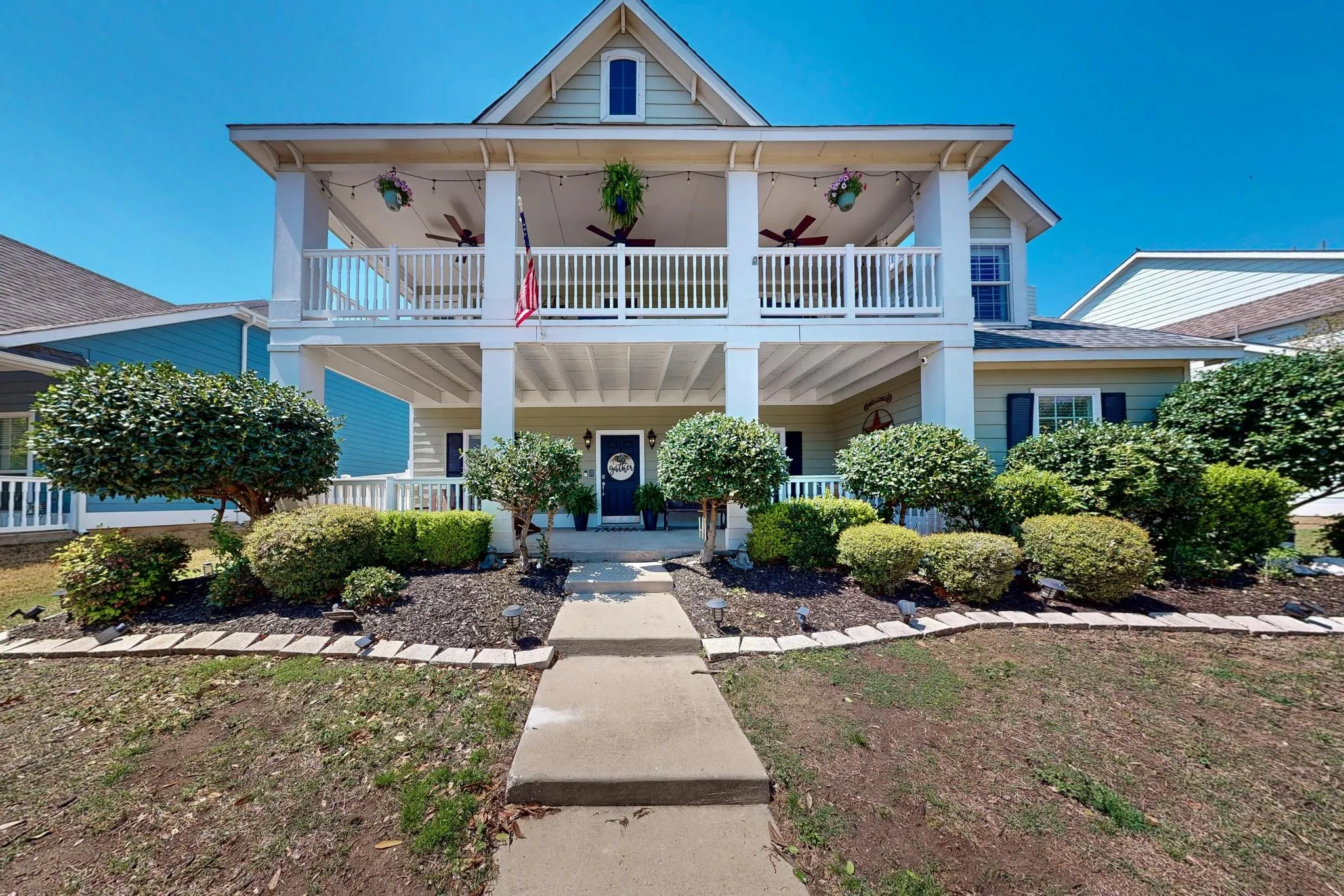 Two-story exterior with a covered porch and upper-level balcony, featuring a gabled roofline and an entryway with a dark blue door