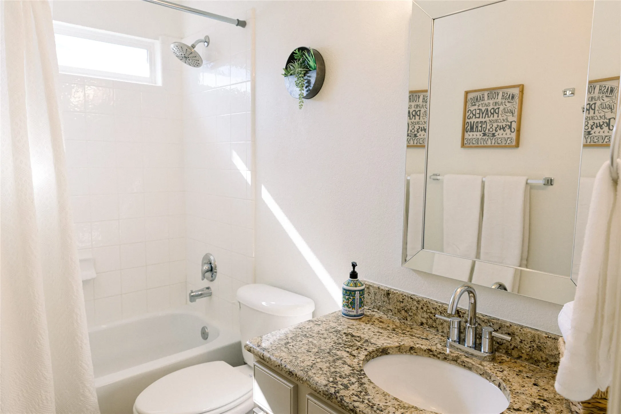 Bathroom featuring a shower-tub combination, a vanity with a granite countertop, an undermount sink, and a framed mirror