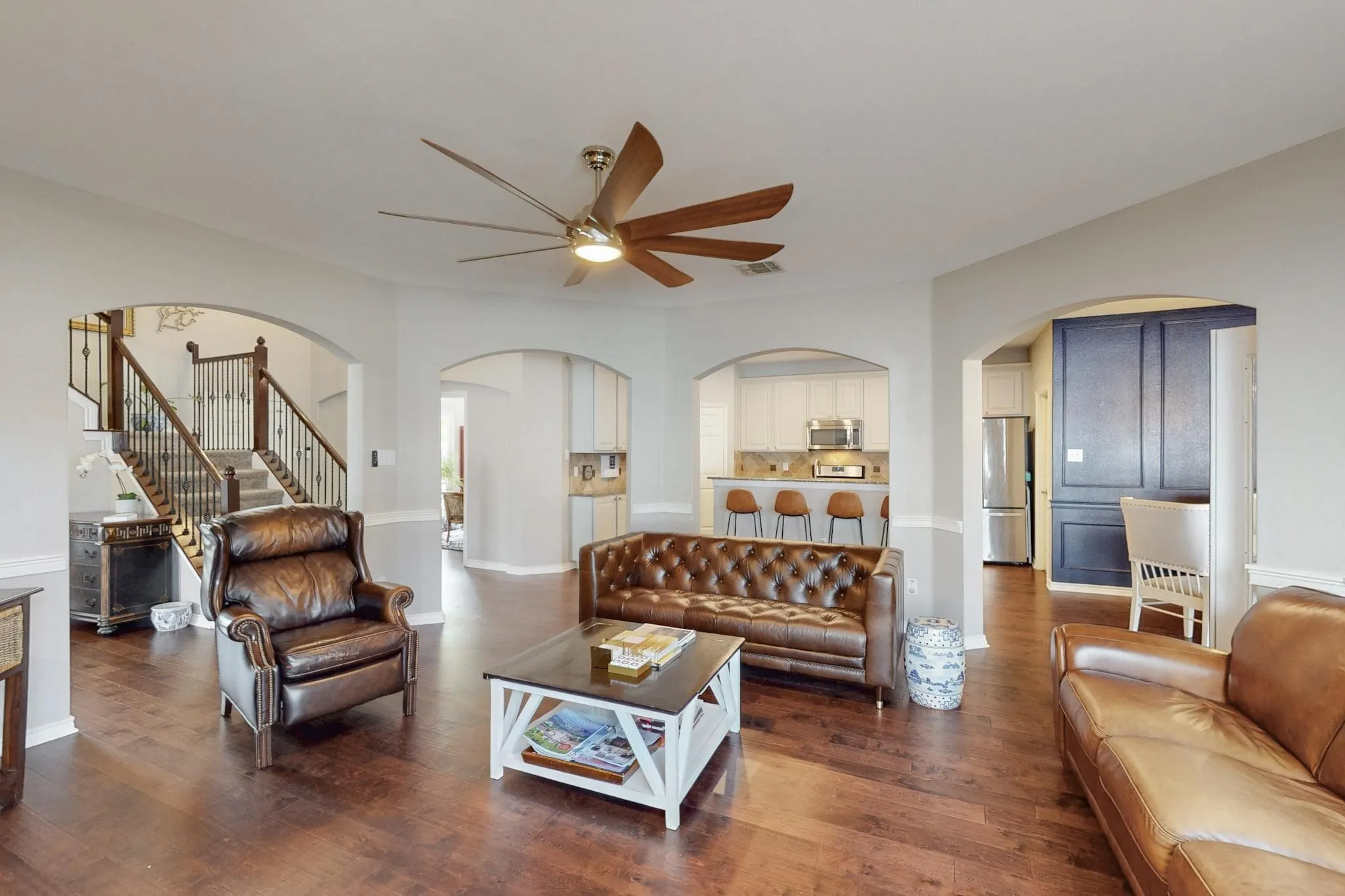 Wood-finish flooring throughout, featuring arched doorways and a ceiling fan with integrated lighting