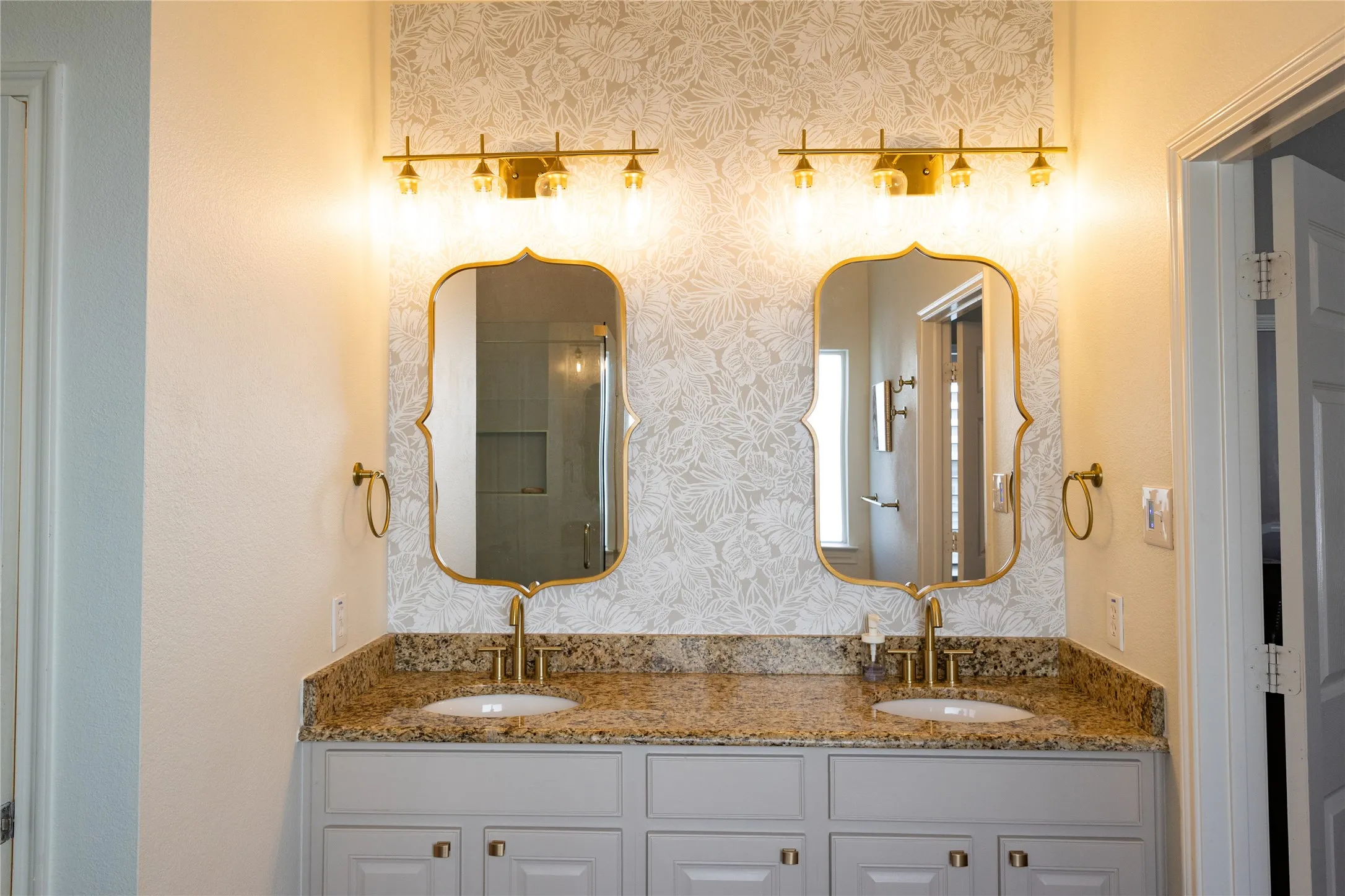 Double vanity with granite countertop, dual undermount sinks, and gold-finish fixtures