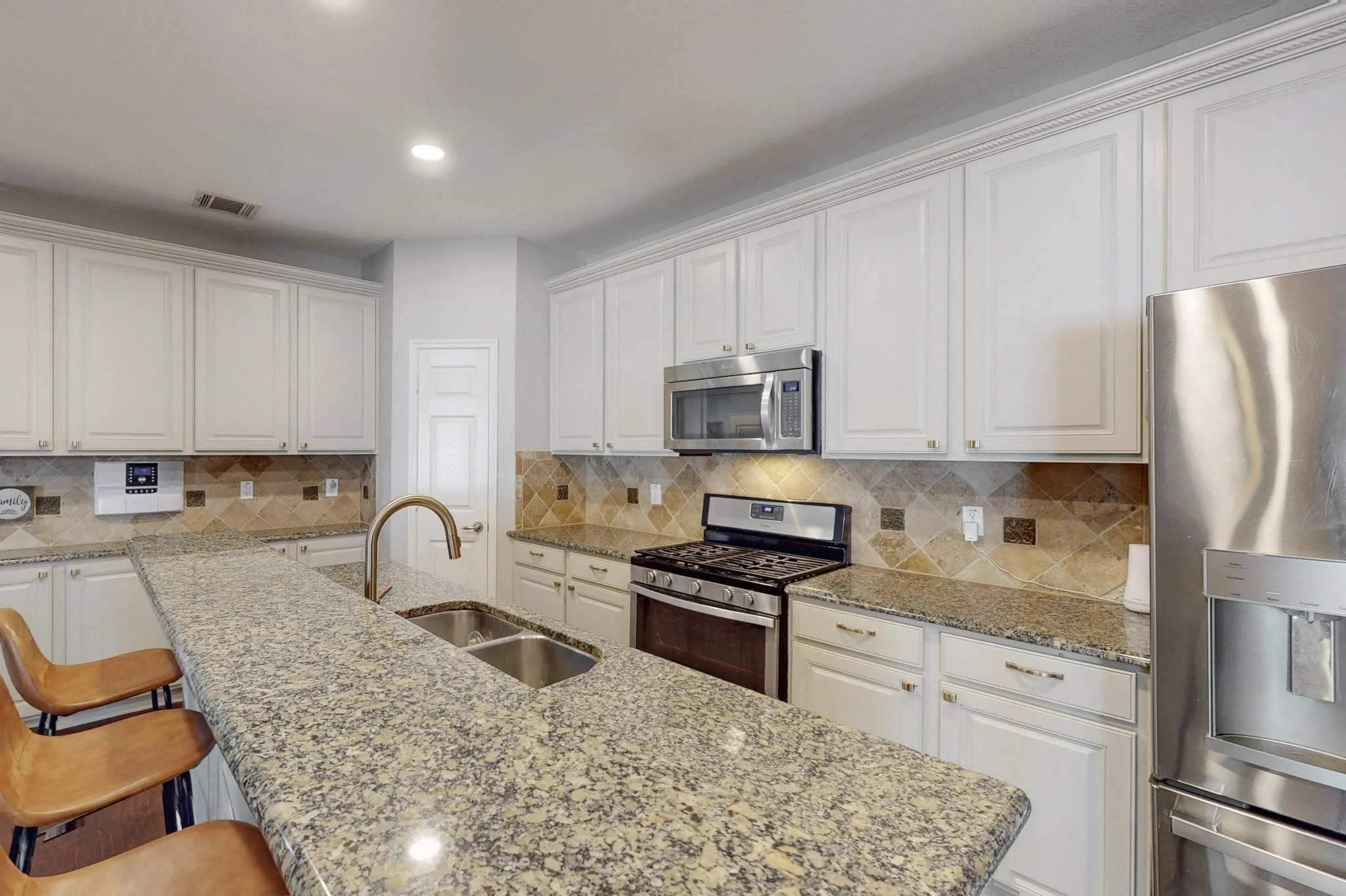 Kitchen featuring extensive white cabinetry, speckled countertops, stainless steel appliances, and a tiled backsplash