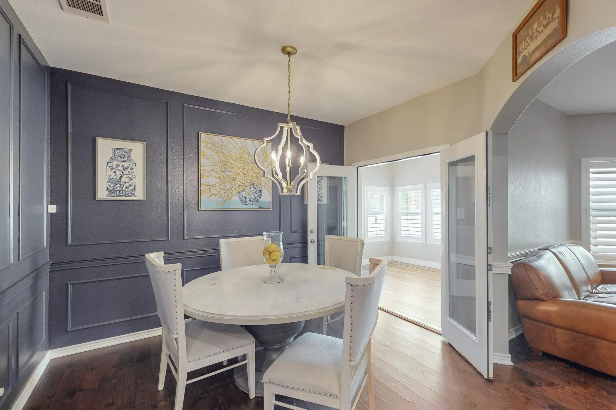 Wall paneling detail with a decorative light fixture and wood-finish flooring