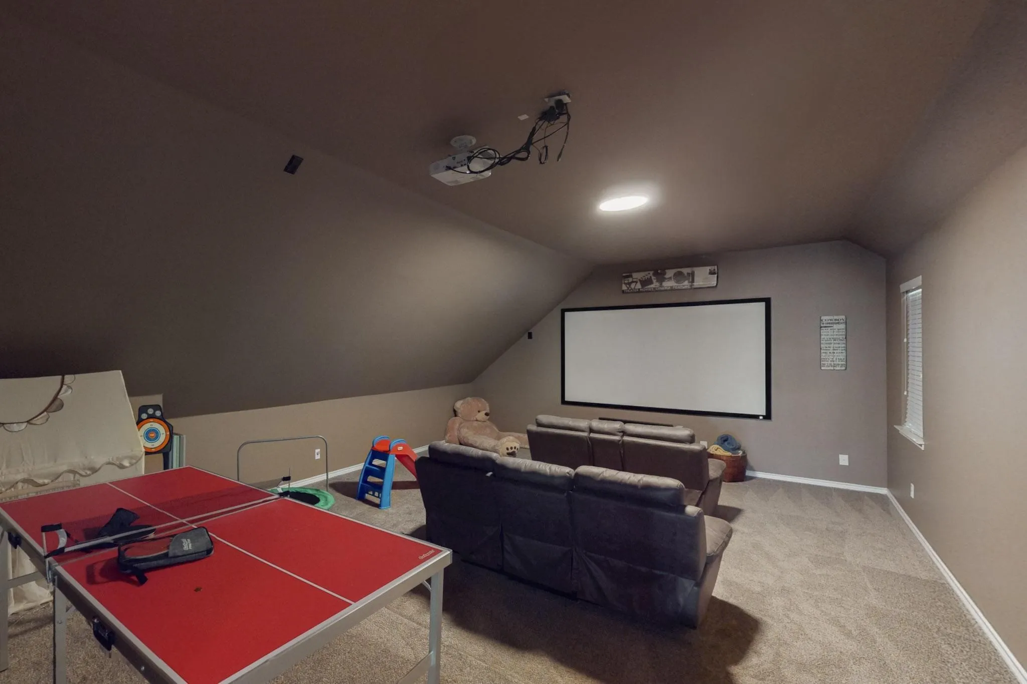 Carpeted bonus room featuring a built-in projection screen, recessed lighting, and a sloped ceiling
