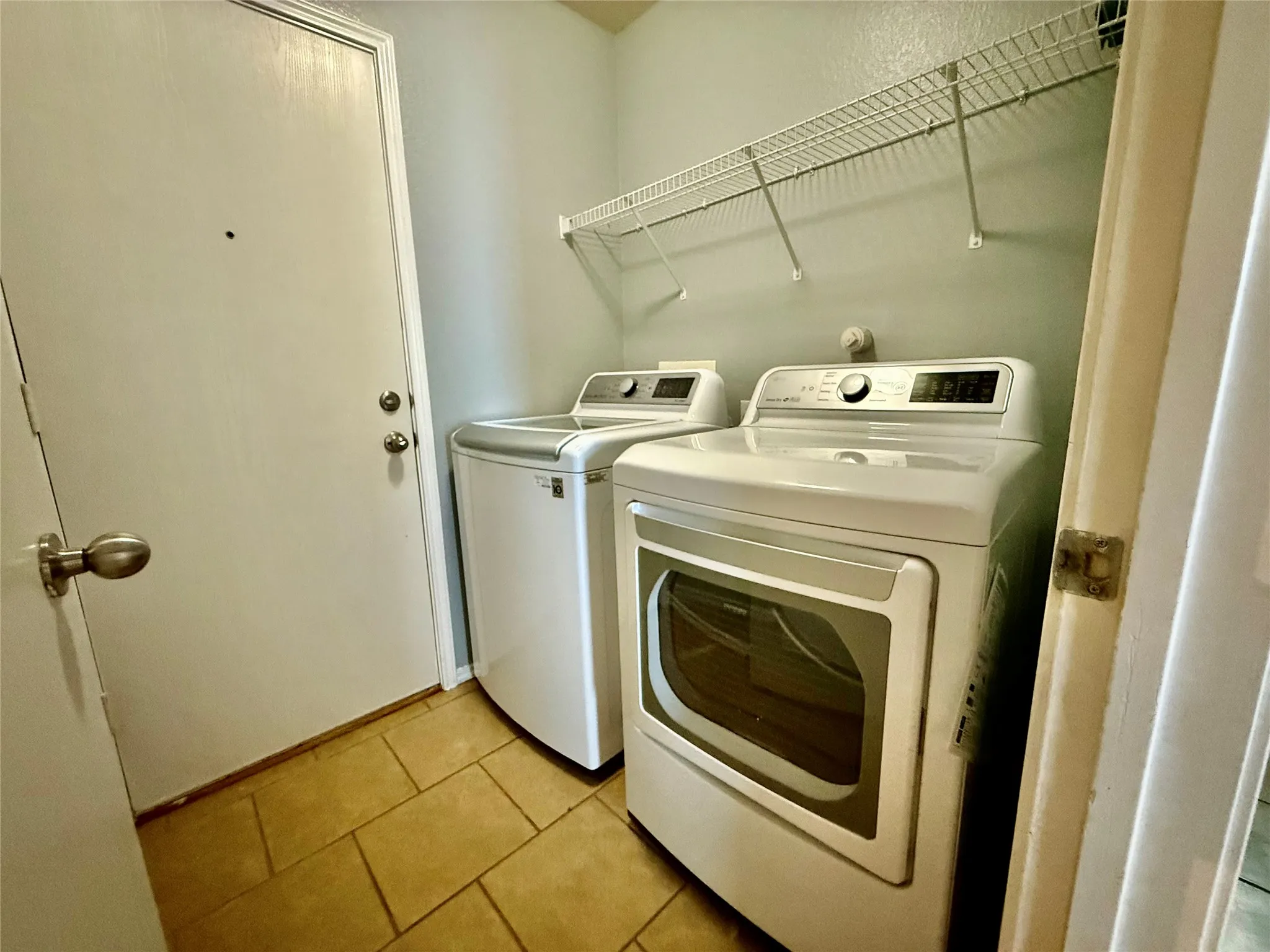 Utility area featuring tile flooring and a white wire shelf