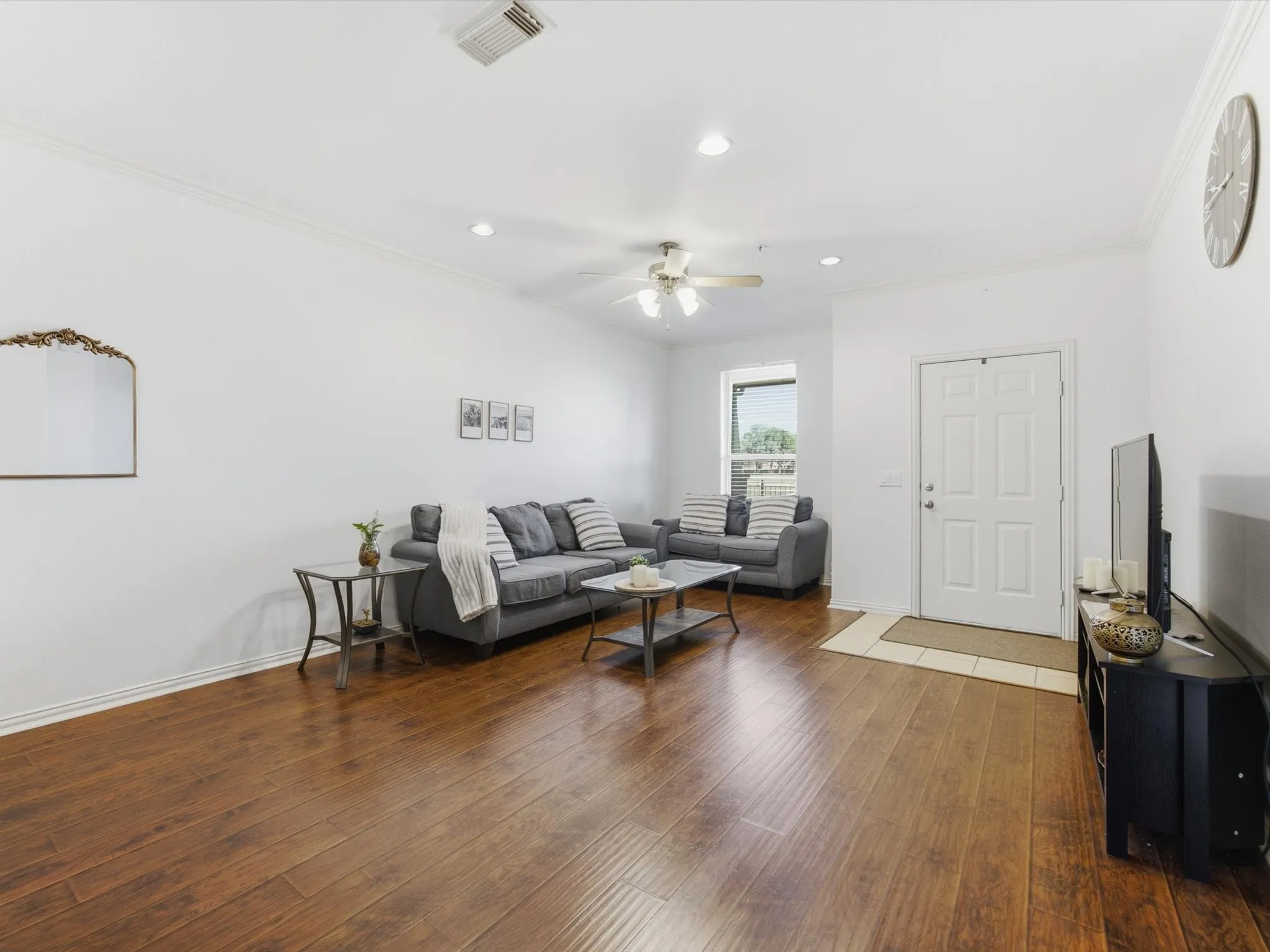 Wood-finish flooring with white baseboards, crown molding, and recessed lighting