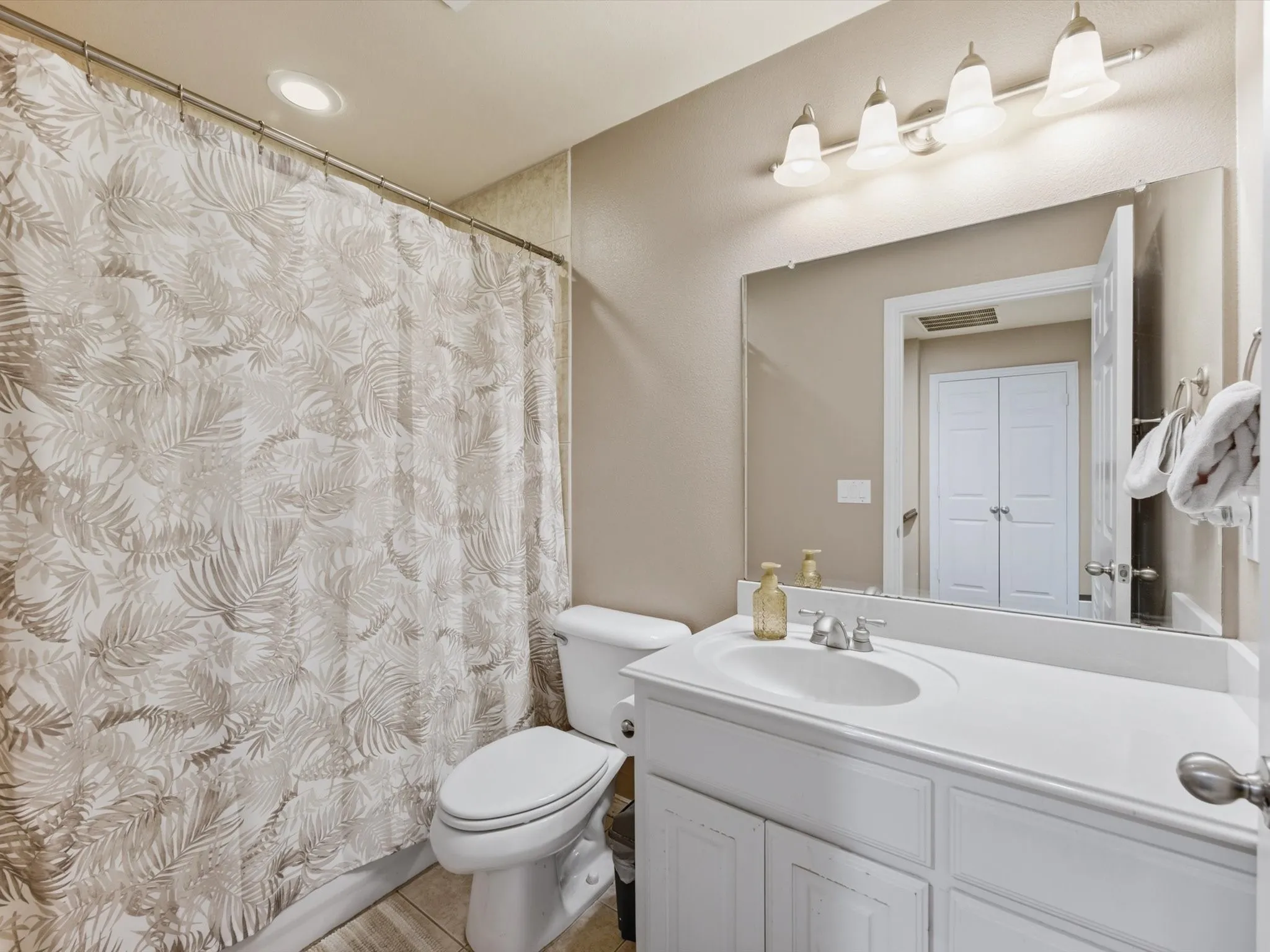 White vanity with integrated sink, chrome faucet, and a large wall-mounted mirror