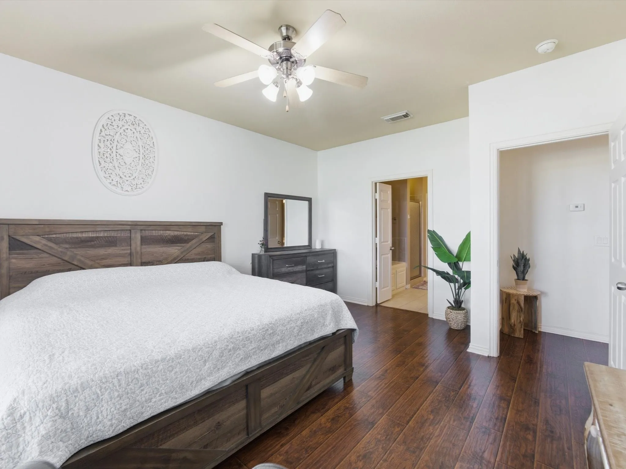 Wood-finish flooring, ceiling fan with integrated lighting, and a doorway leading to an additional space