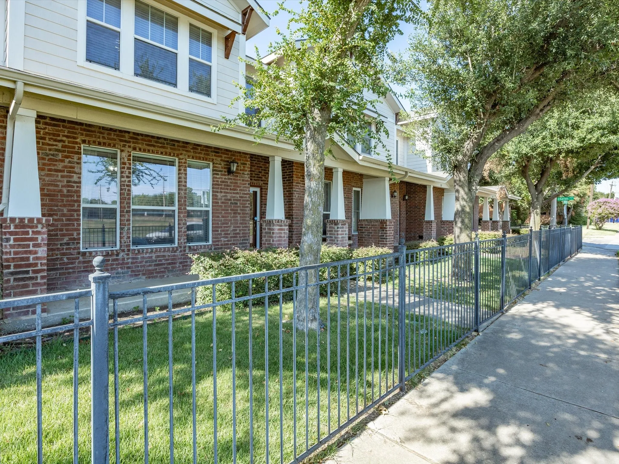 Brick and siding exterior featuring multiple windows and a black metal fence