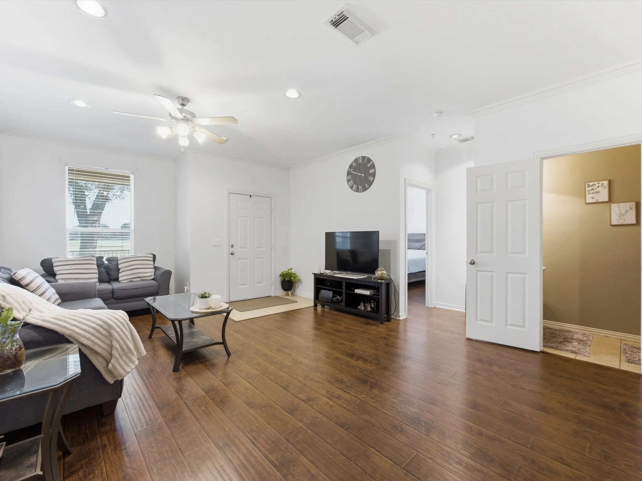 Wood-finish flooring, recessed lighting, ceiling fan, and crown molding