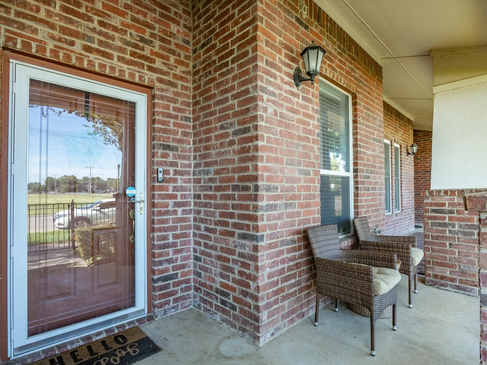 Brick exterior with contrasting white trim, covered porch, and wall-mounted exterior lighting