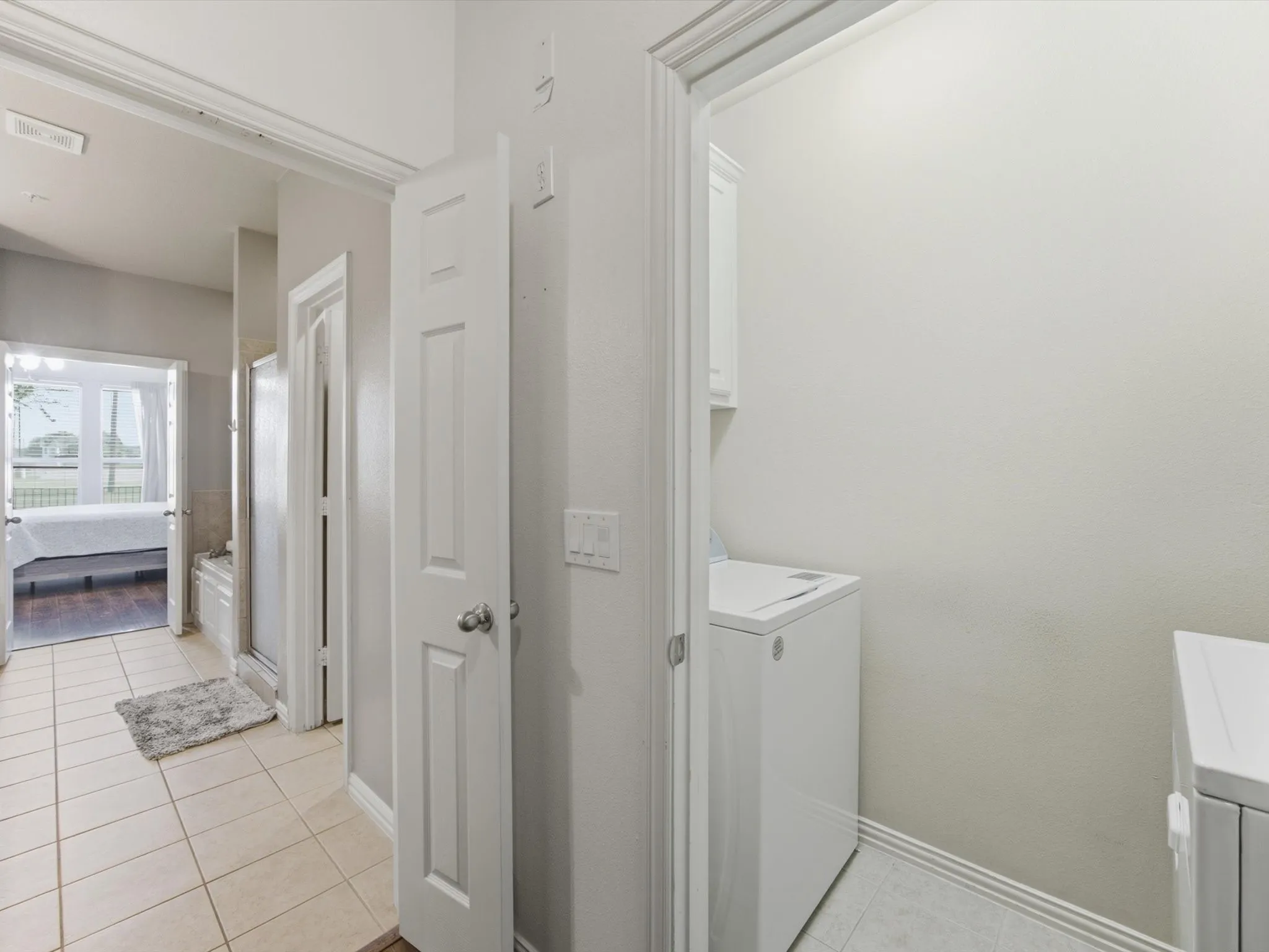 Hallway featuring tile flooring, white interior doors, and a laundry area with built-in storage