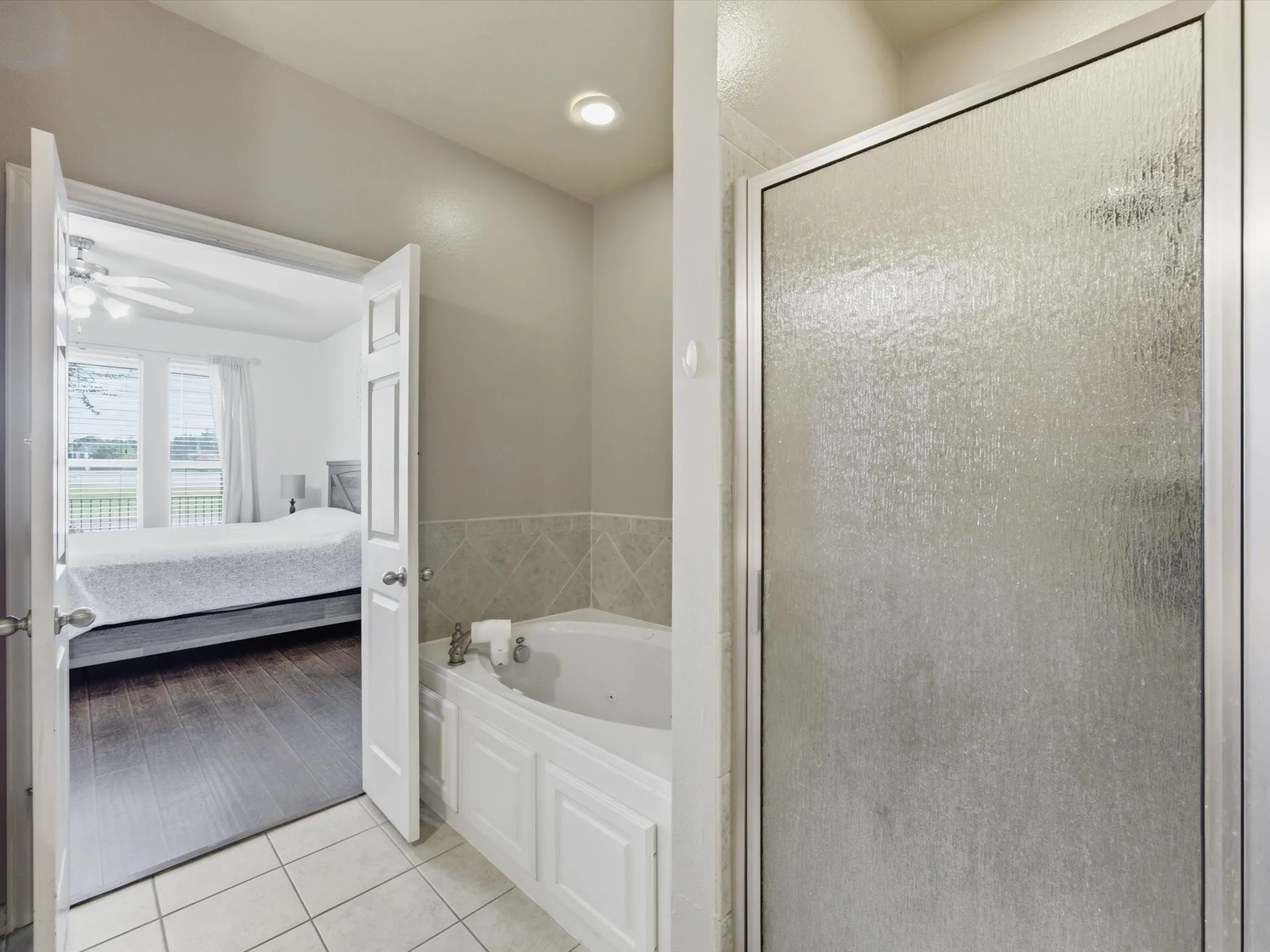 Bathroom with a built-in jetted tub, ceramic tile flooring, and a glass-enclosed shower