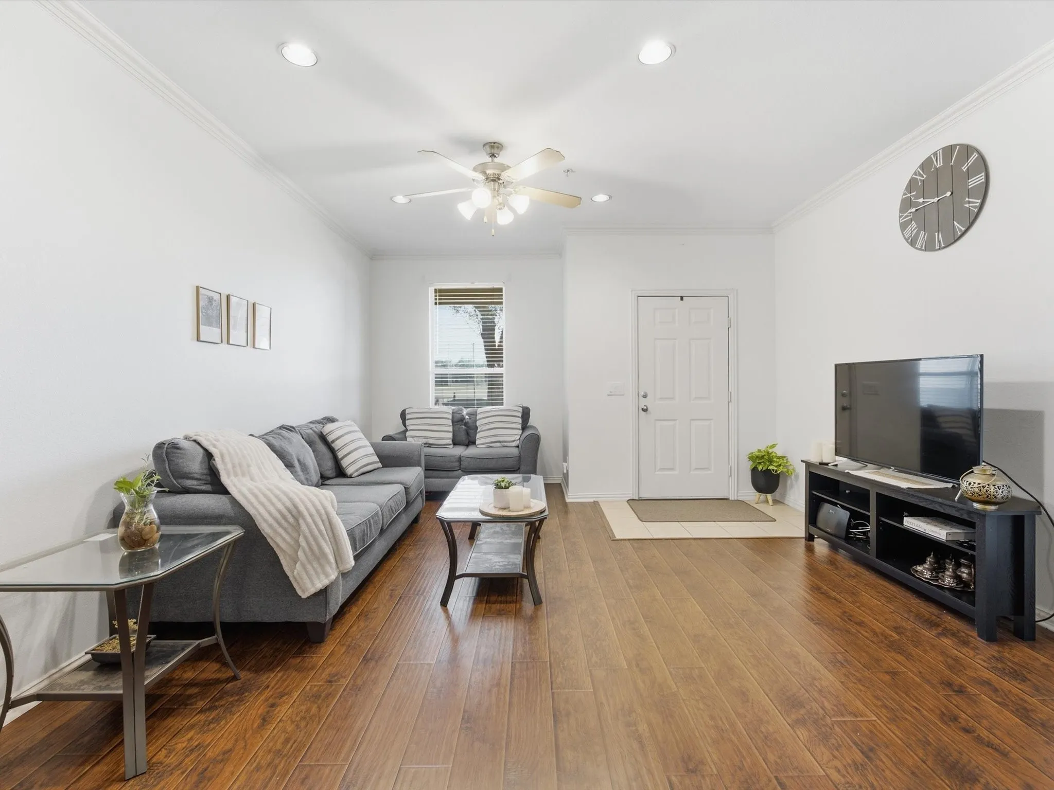 Wood-finish flooring throughout, recessed lighting, crown molding, ceiling fan, and a paneled entry door