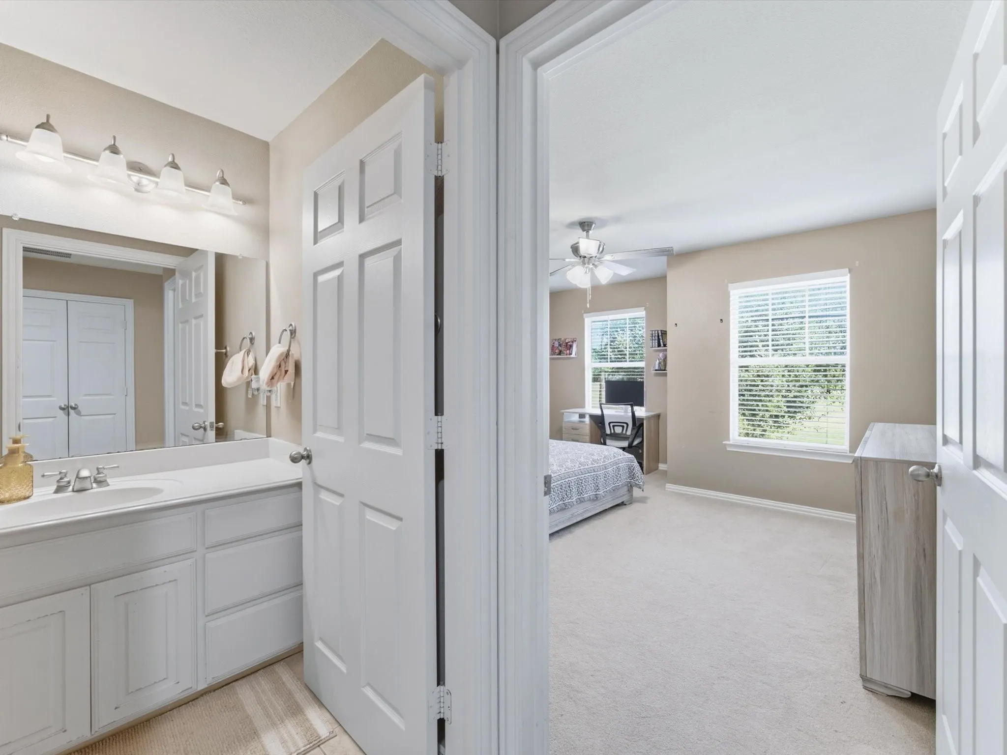 Bathroom vanity with a single basin sink, wall-mounted mirror, and overhead lighting