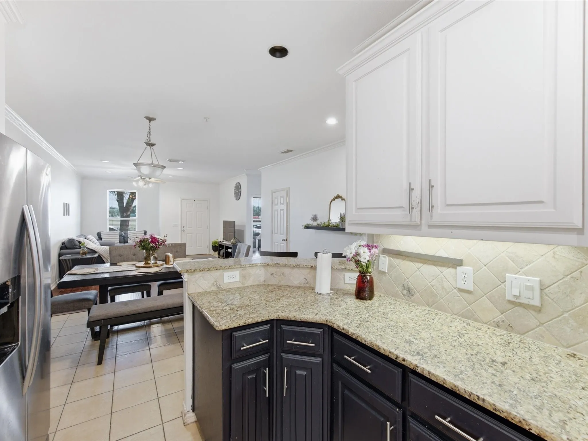 Kitchen featuring granite countertops, a tiled backsplash, contrasting cabinetry, and stainless steel appliances