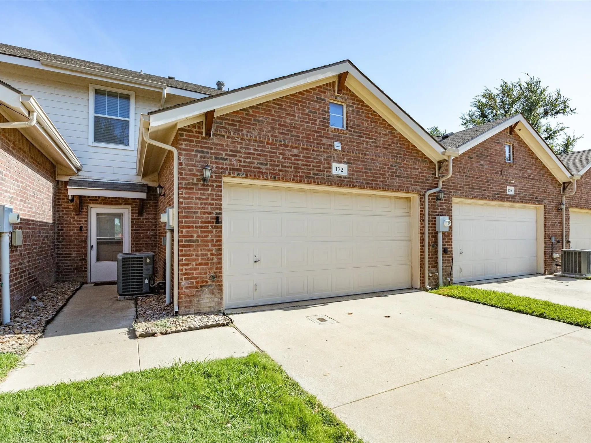 Brick exterior with an attached garage, concrete driveway, and concrete walkway