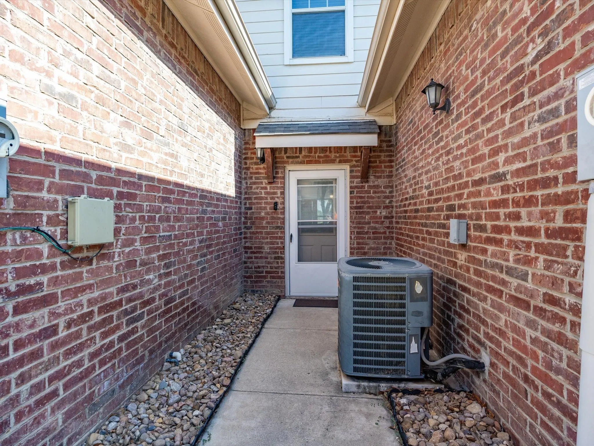 Brick exterior with a concrete walkway and gravel landscaping
