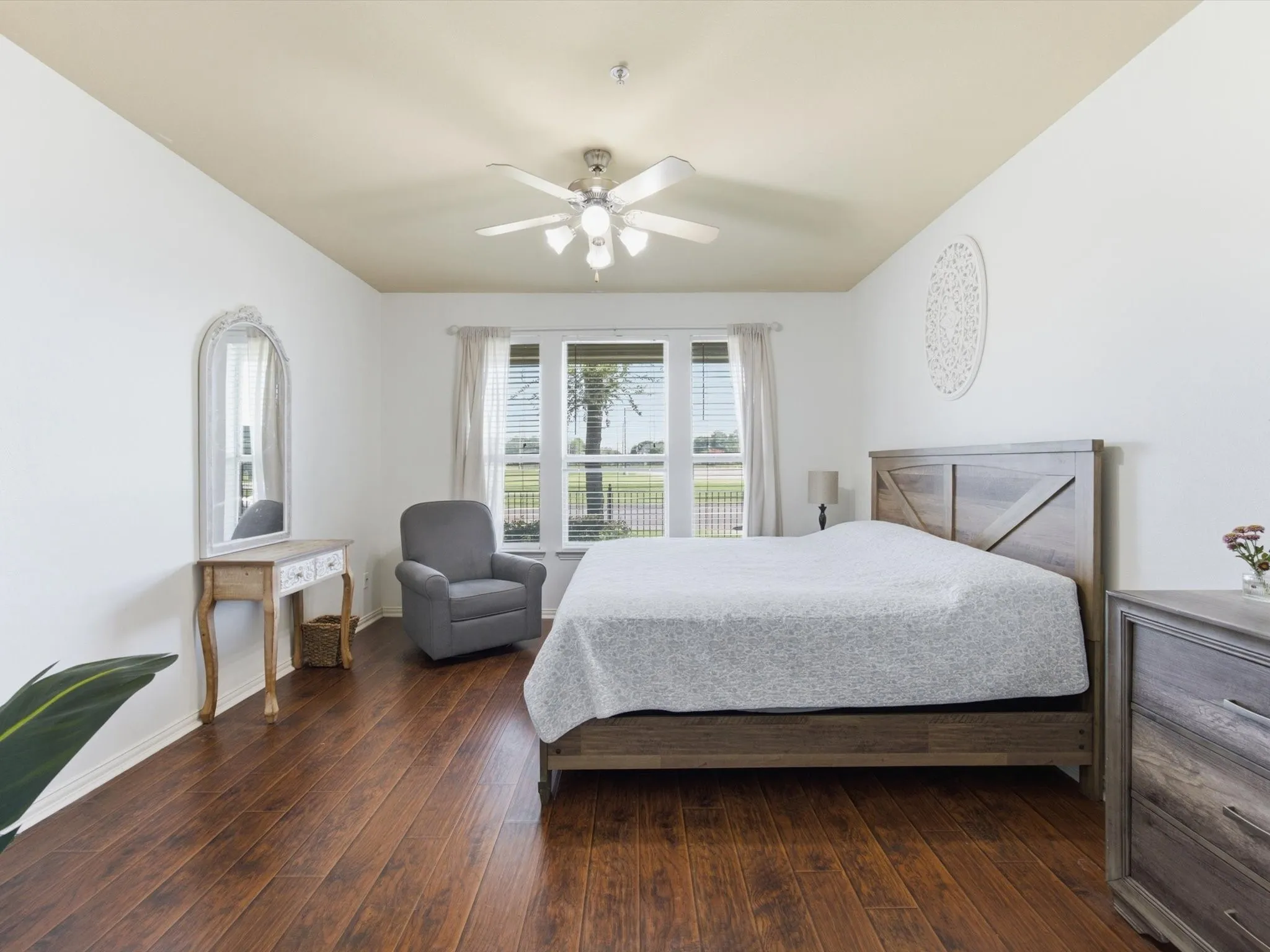 Wood-finish flooring, ceiling fan with integrated lighting, expansive window, white walls, and a light-colored ceiling