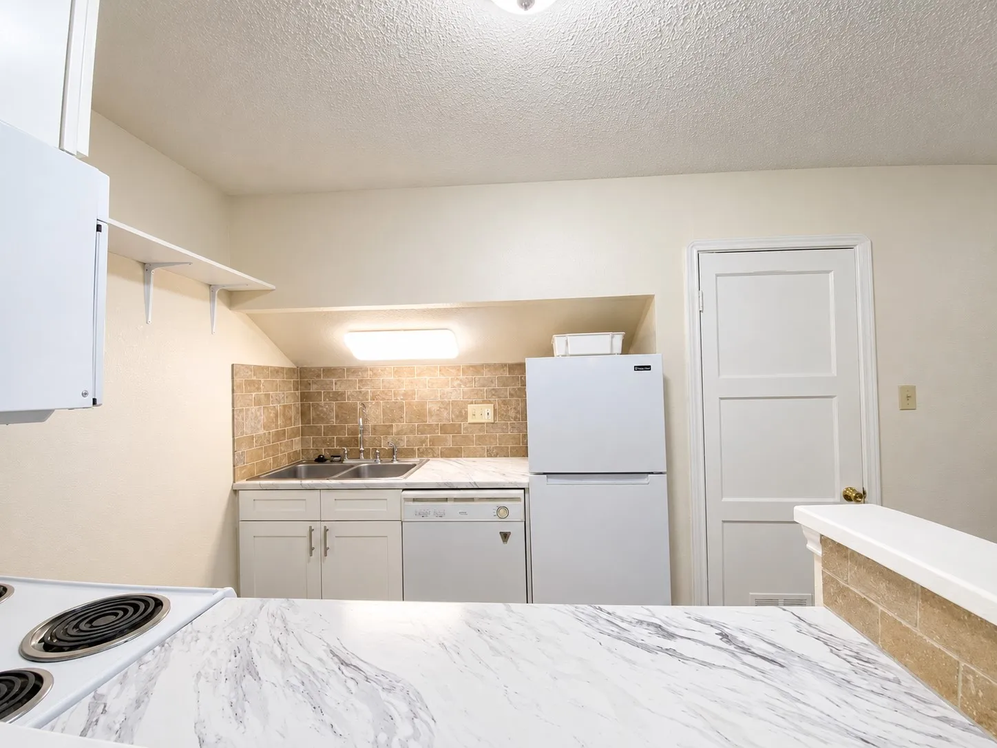 White cabinetry, dual basin sink, integrated dishwasher, white refrigerator, and tile backsplash