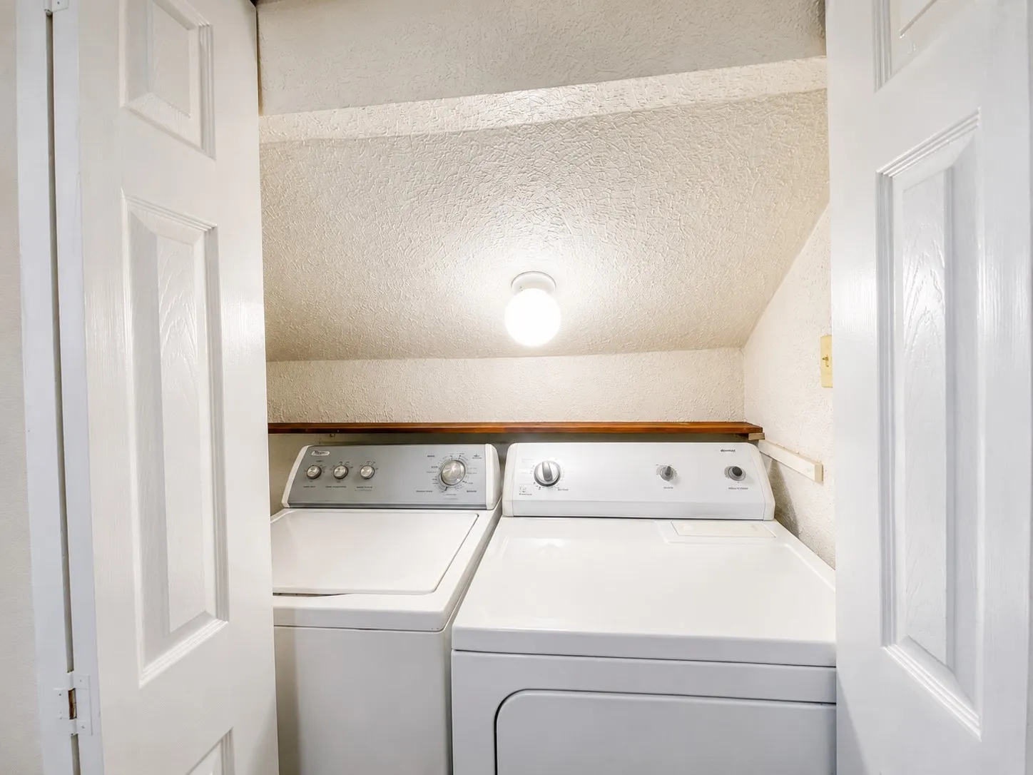 Dedicated laundry area with a top-load washing machine and front-load dryer