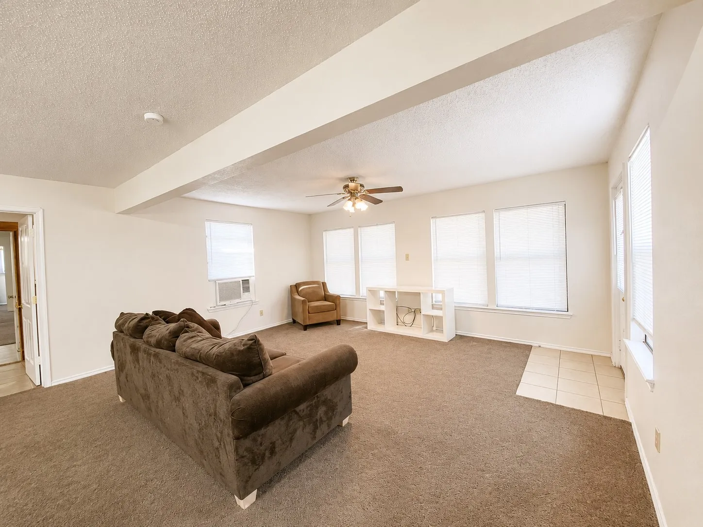 Spacious interior with neutral-toned walls, multiple windows, and a ceiling fan