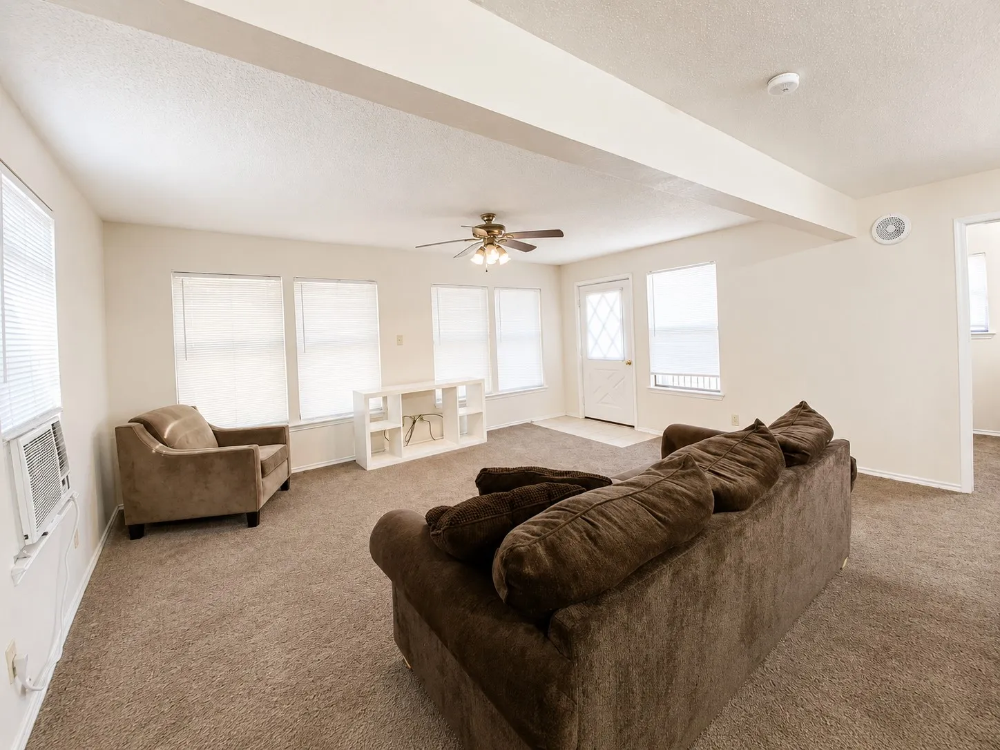 Carpeted living space with multiple windows, an exterior door, and a ceiling fan