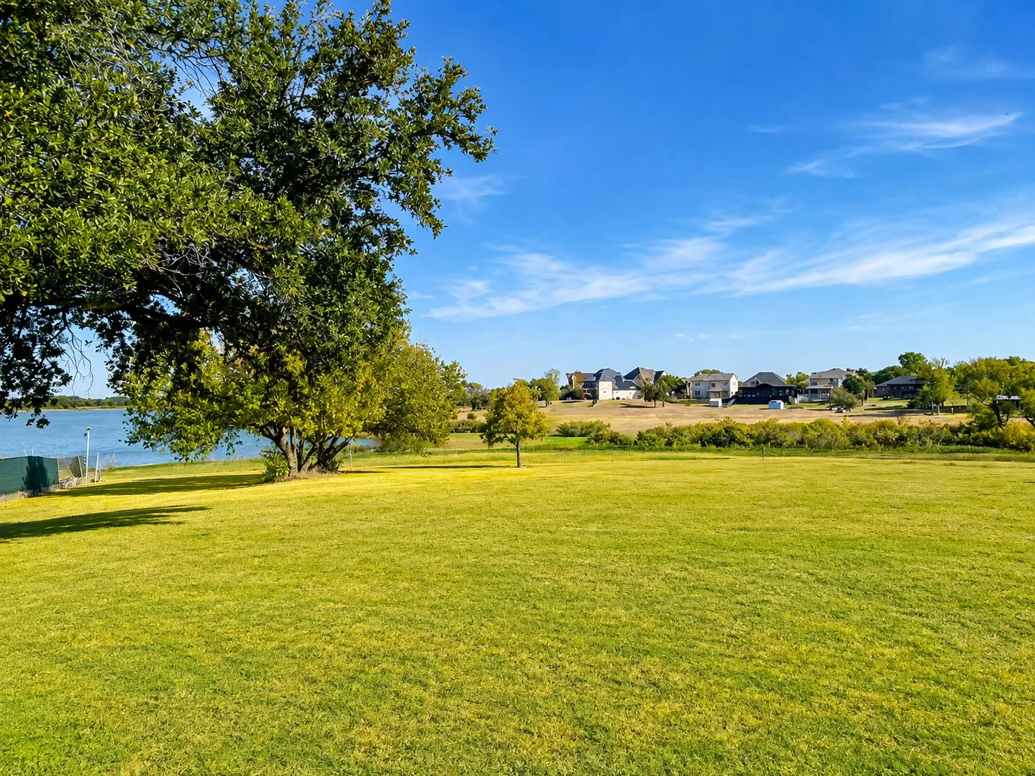 Expansive green lawn with a tree, bordered by a body of water