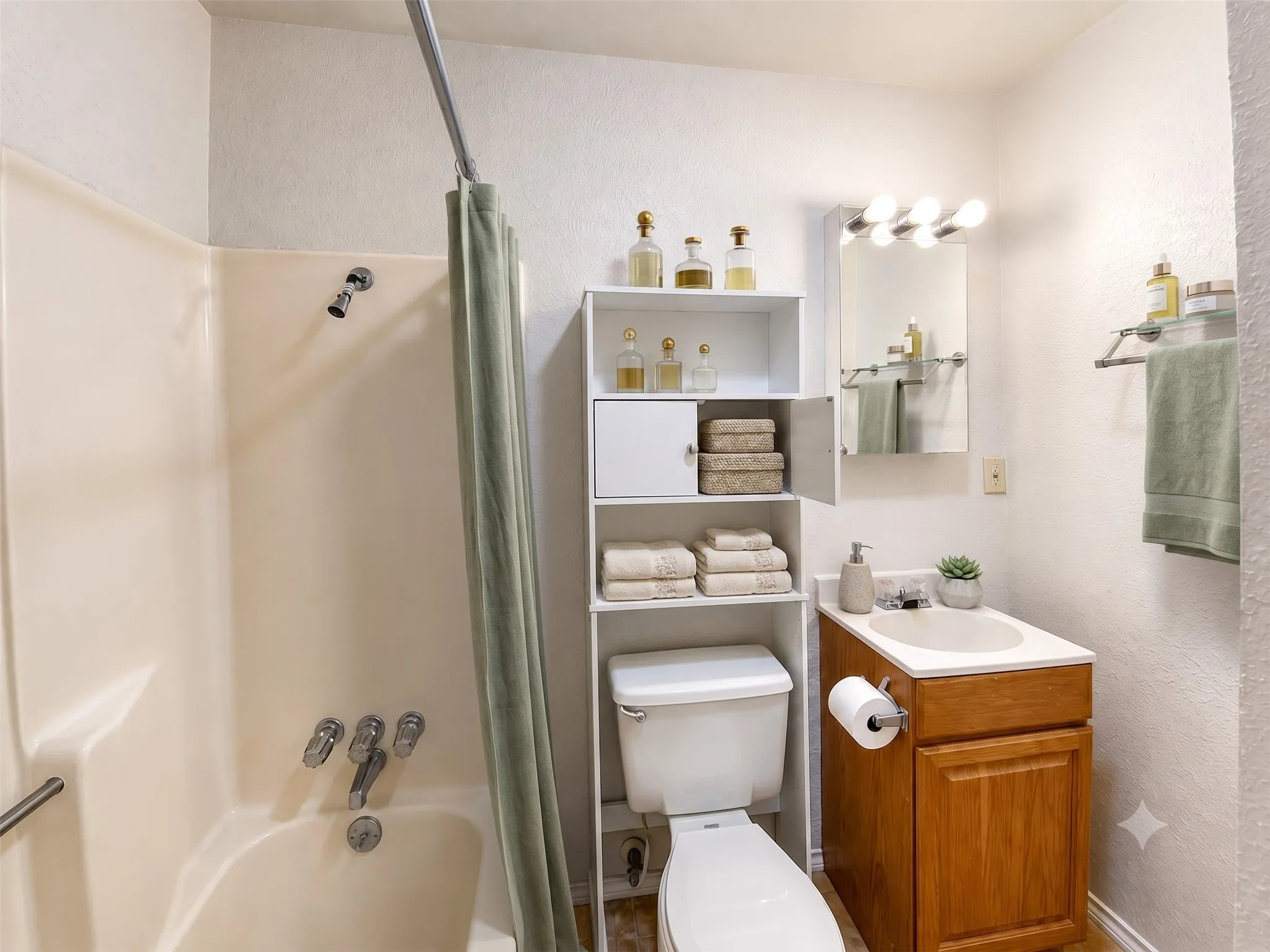Tub-shower combination with chrome fixtures, vanity with wood-finish cabinetry, and a mirrored medicine cabinet with integrated lighting- Virtually Staged