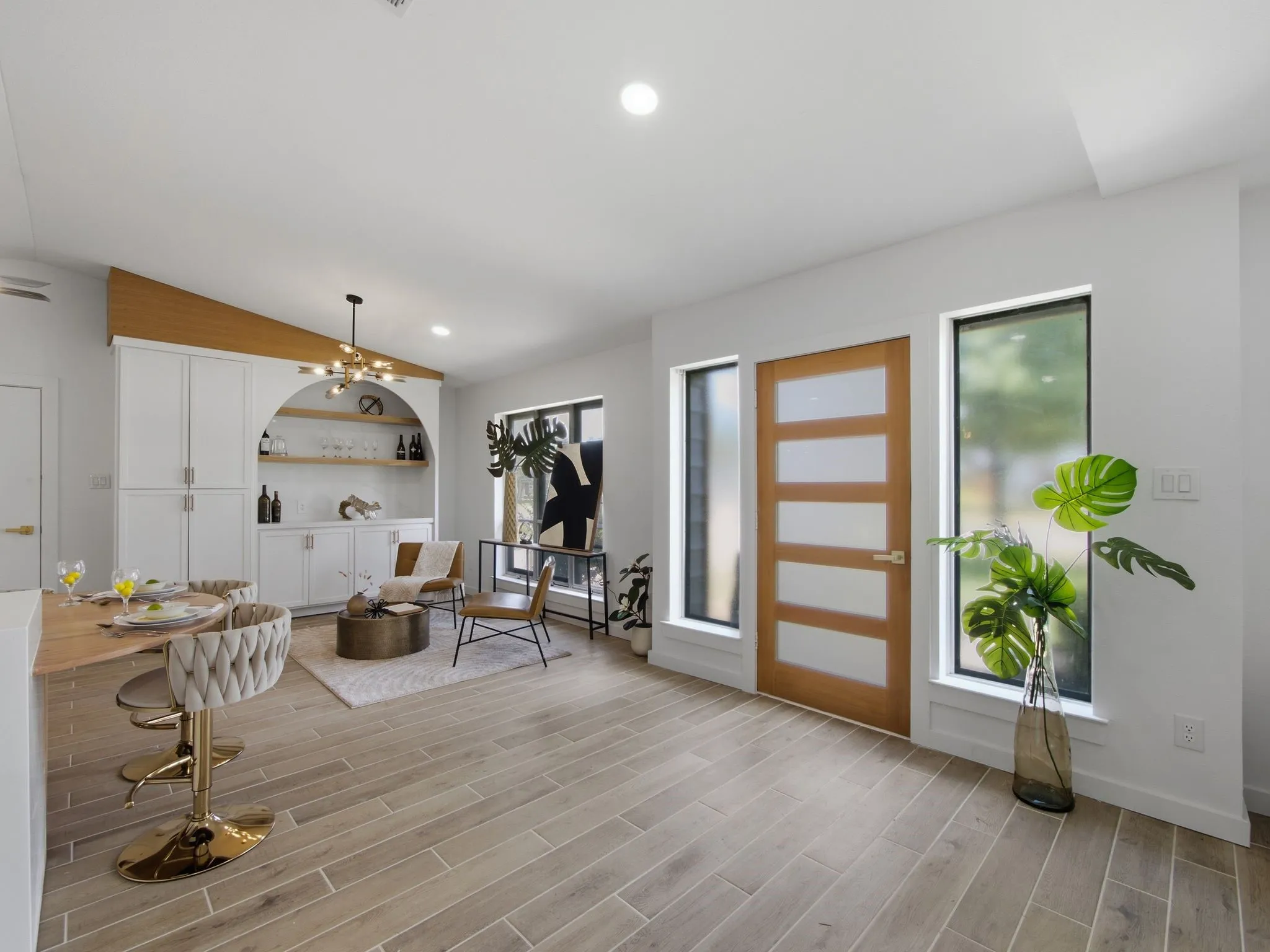 Wood-finish flooring, built-in cabinetry with an arched recess, modern light fixture, and contemporary windows