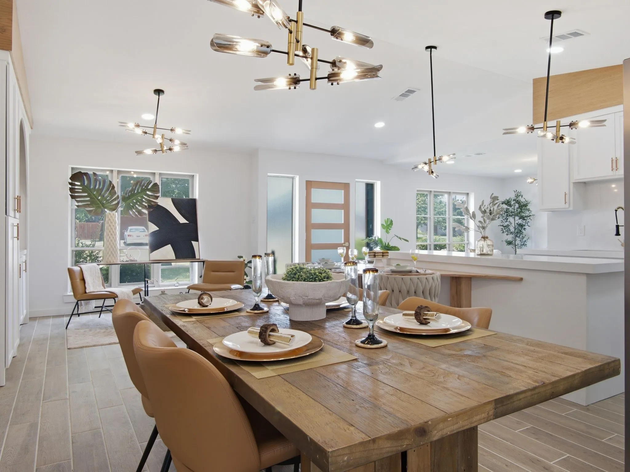 Wood-finish flooring throughout, modern chandeliers, white cabinetry, and large windows