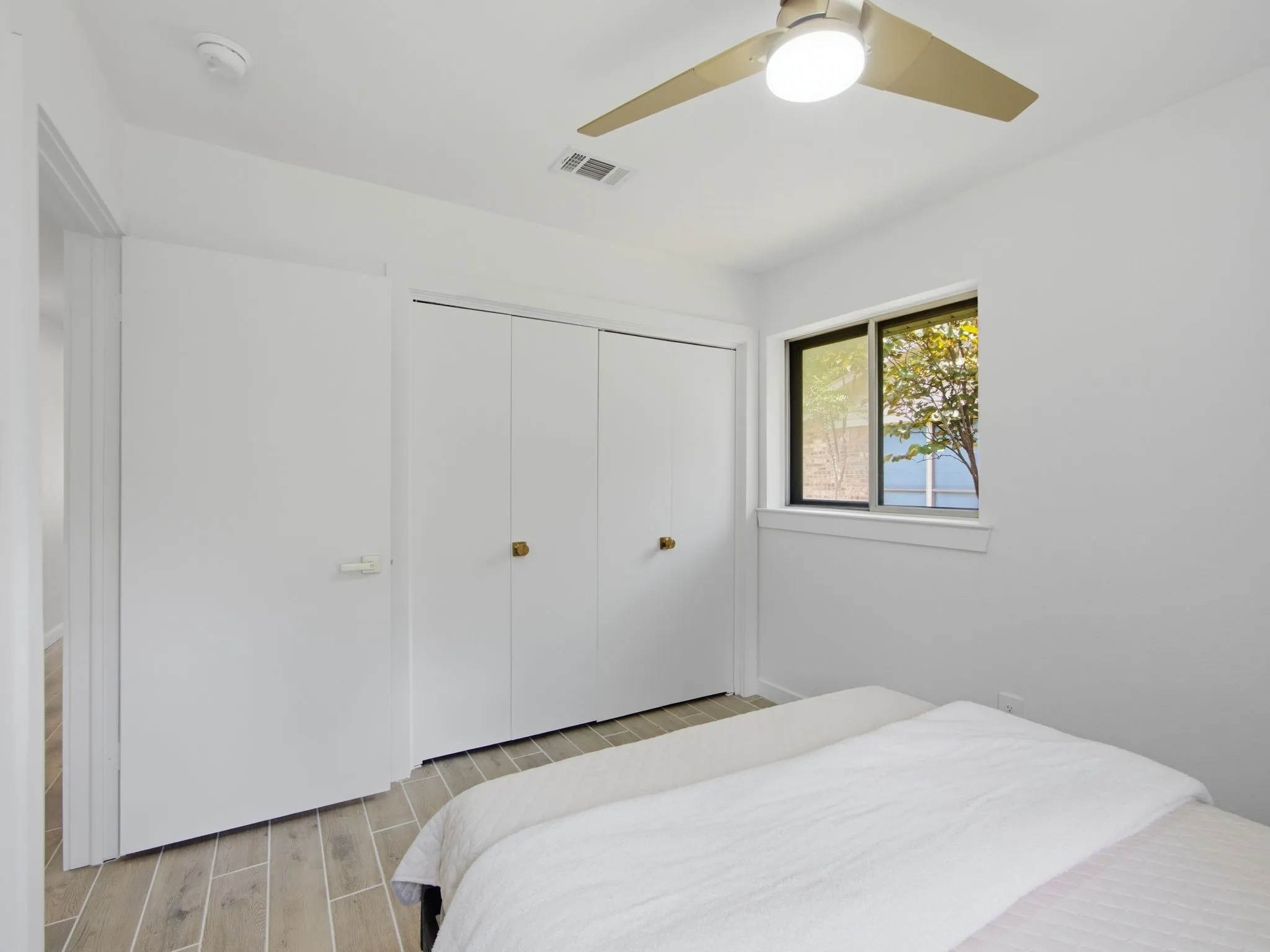 Wood-finish flooring, white walls, and a ceiling fan with integrated lighting