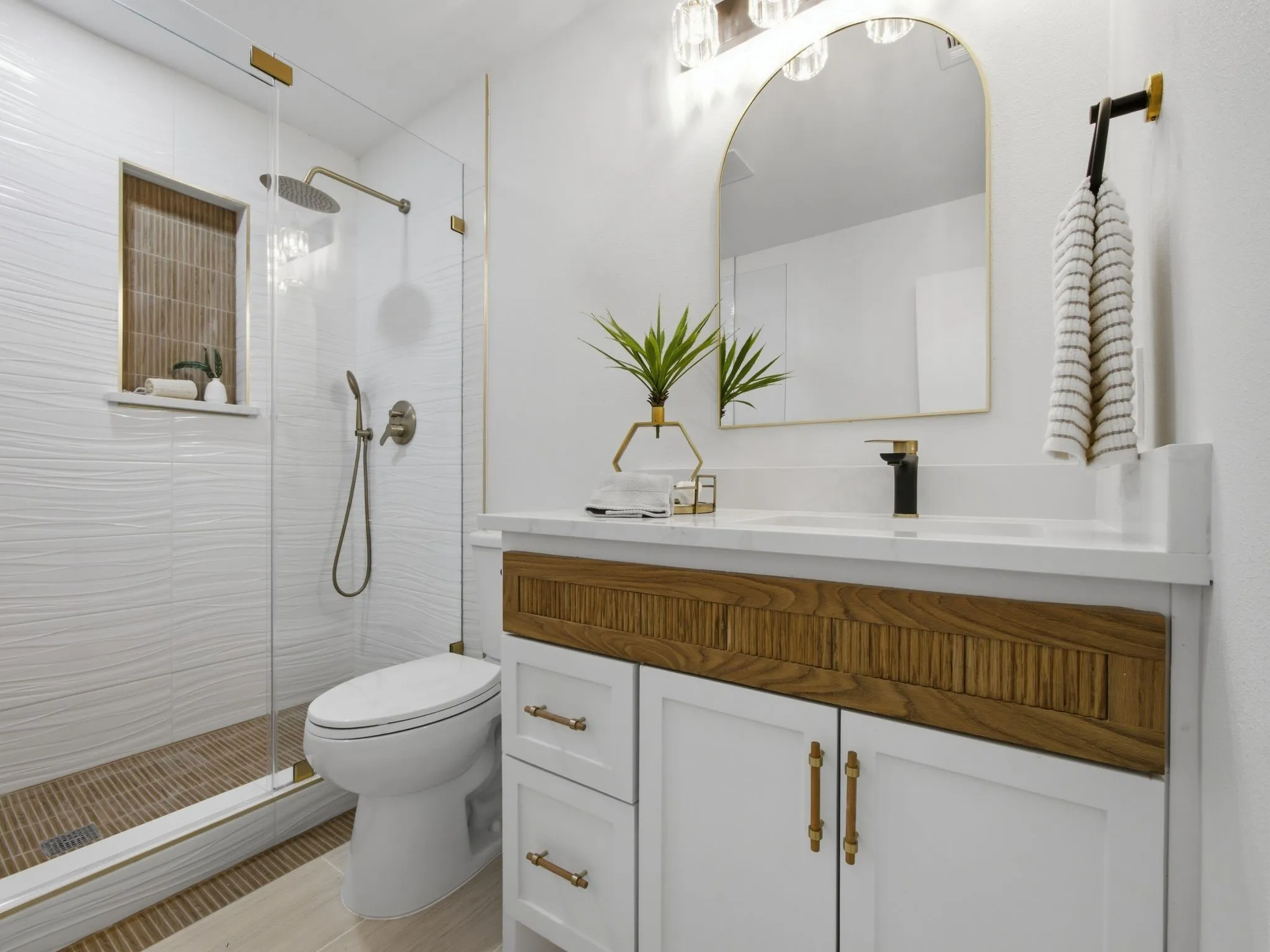 Glass-enclosed shower with a rainfall showerhead, textured wall tile, and a built-in niche