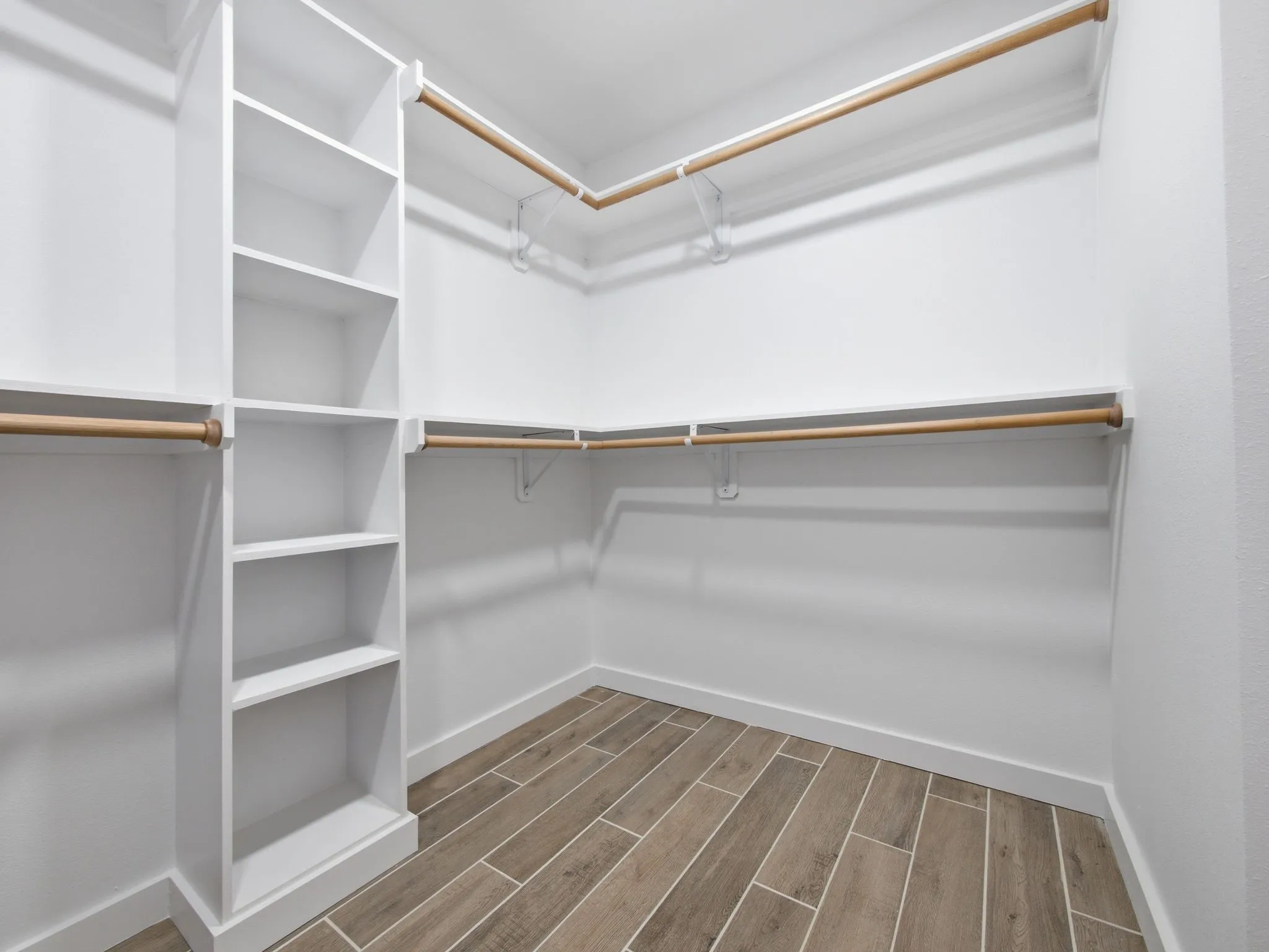 Built-in shelving unit, multiple clothing rods, and wood-finish flooring