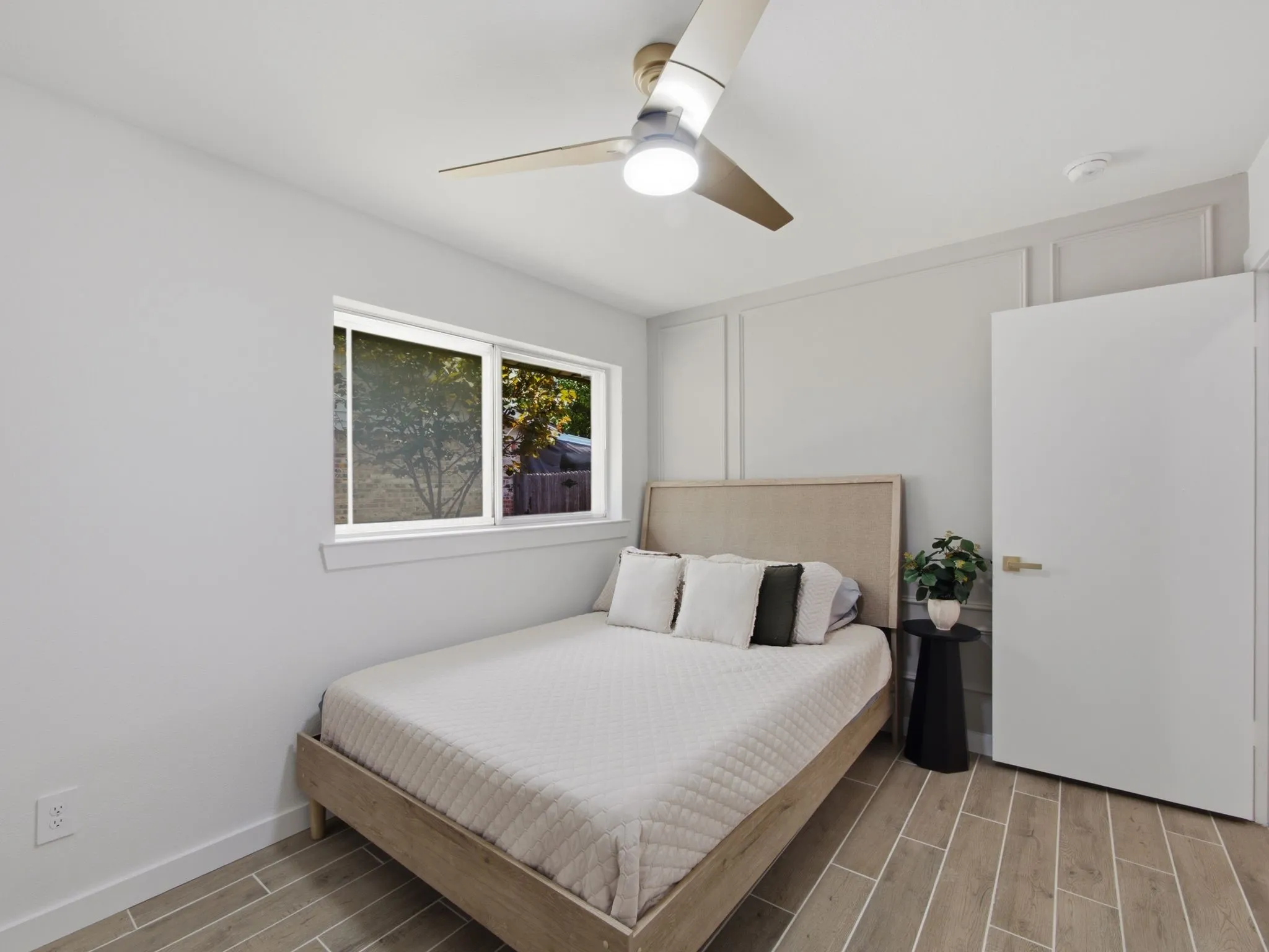 Room featuring a ceiling fan with integrated lighting, wood-finish flooring, and panel accent wall detailing