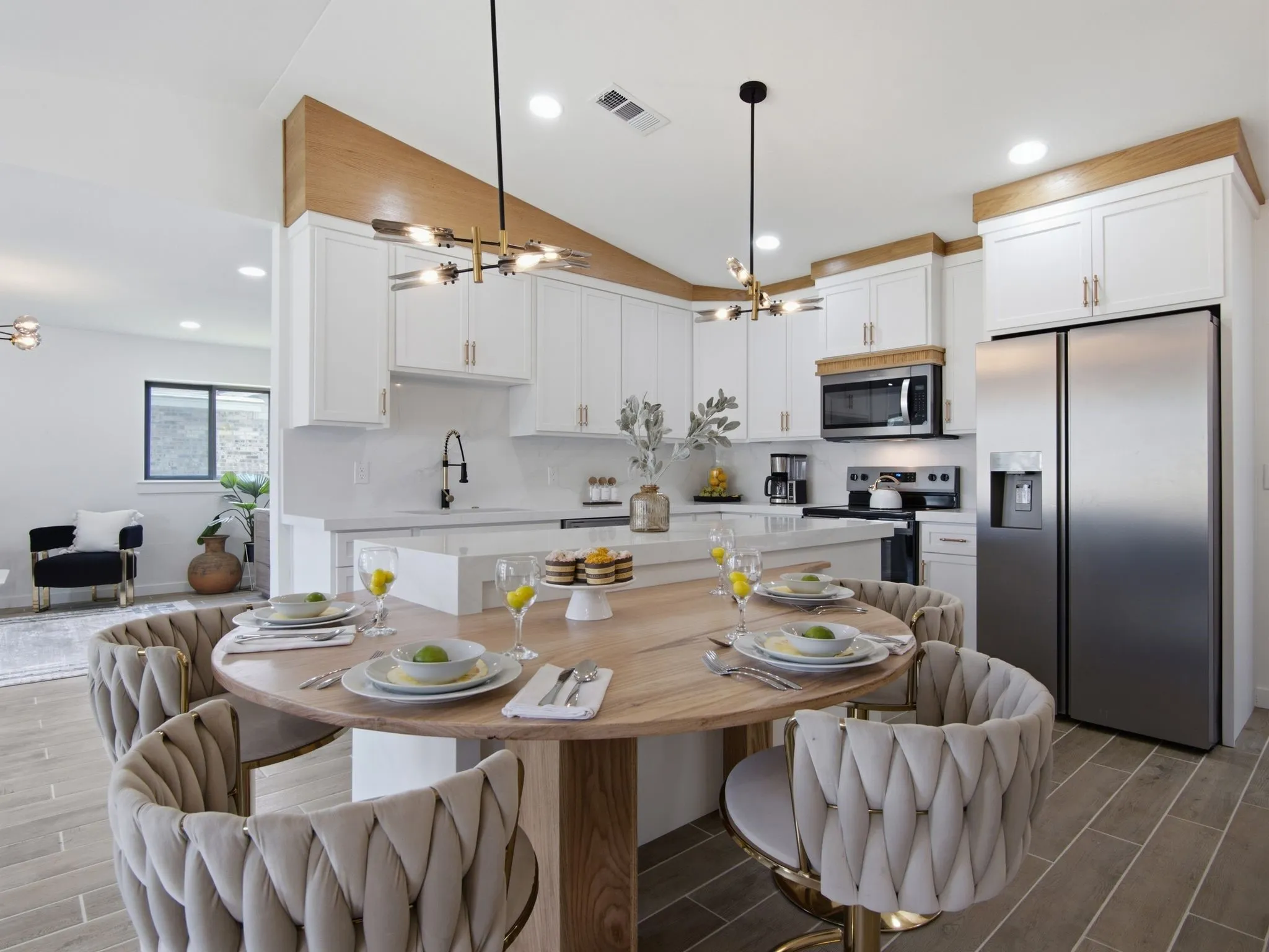 Open-concept kitchen featuring white shaker cabinetry, stainless steel appliances, and a central island with an integrated dining area