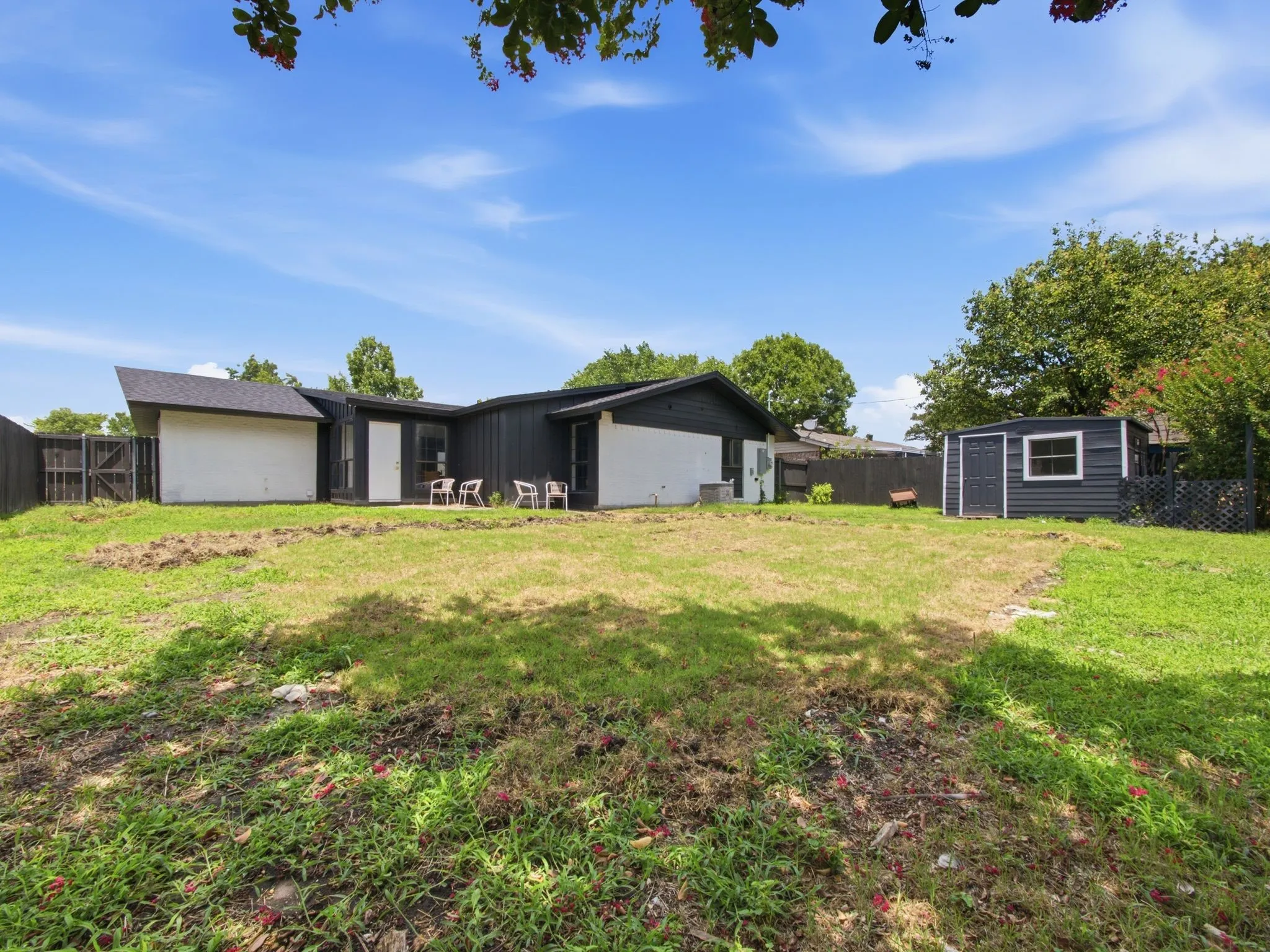 Expansive backyard with a storage shed, wood privacy fence, and mature perimeter trees