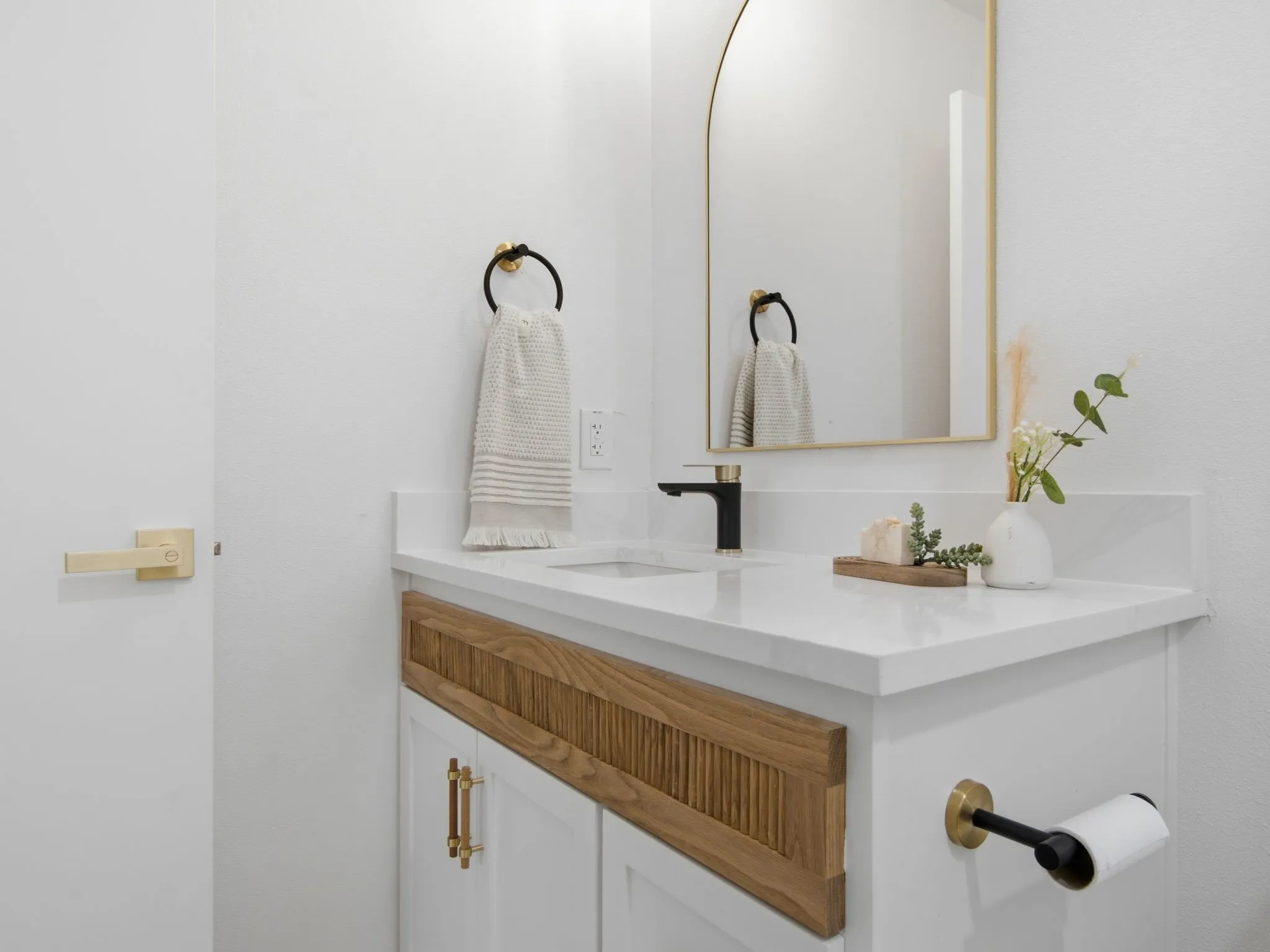 White vanity with wood-finish paneling, an undermount sink, and a black faucet