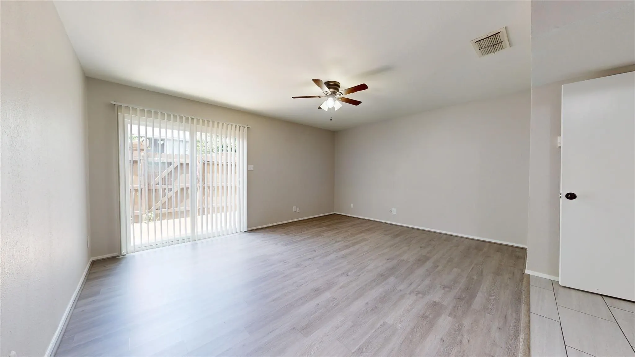 Expansive interior with wood-finish flooring, a ceiling fan, and light-toned walls