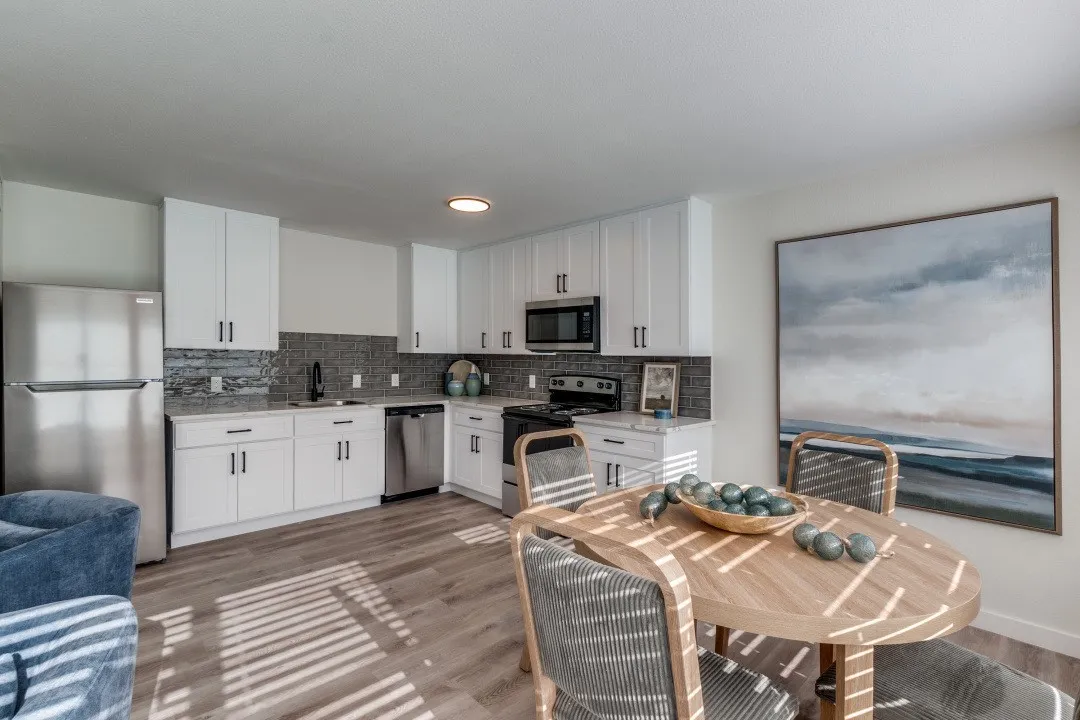Kitchen featuring white cabinetry, stainless steel appliances, a dark tile backsplash, and light-toned wood-finish flooring