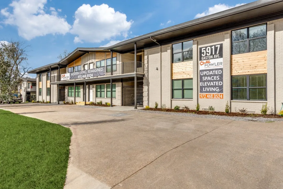 Contemporary multi-story building featuring light-colored brick facade, wood panel accents, and expansive dark-trimmed windows