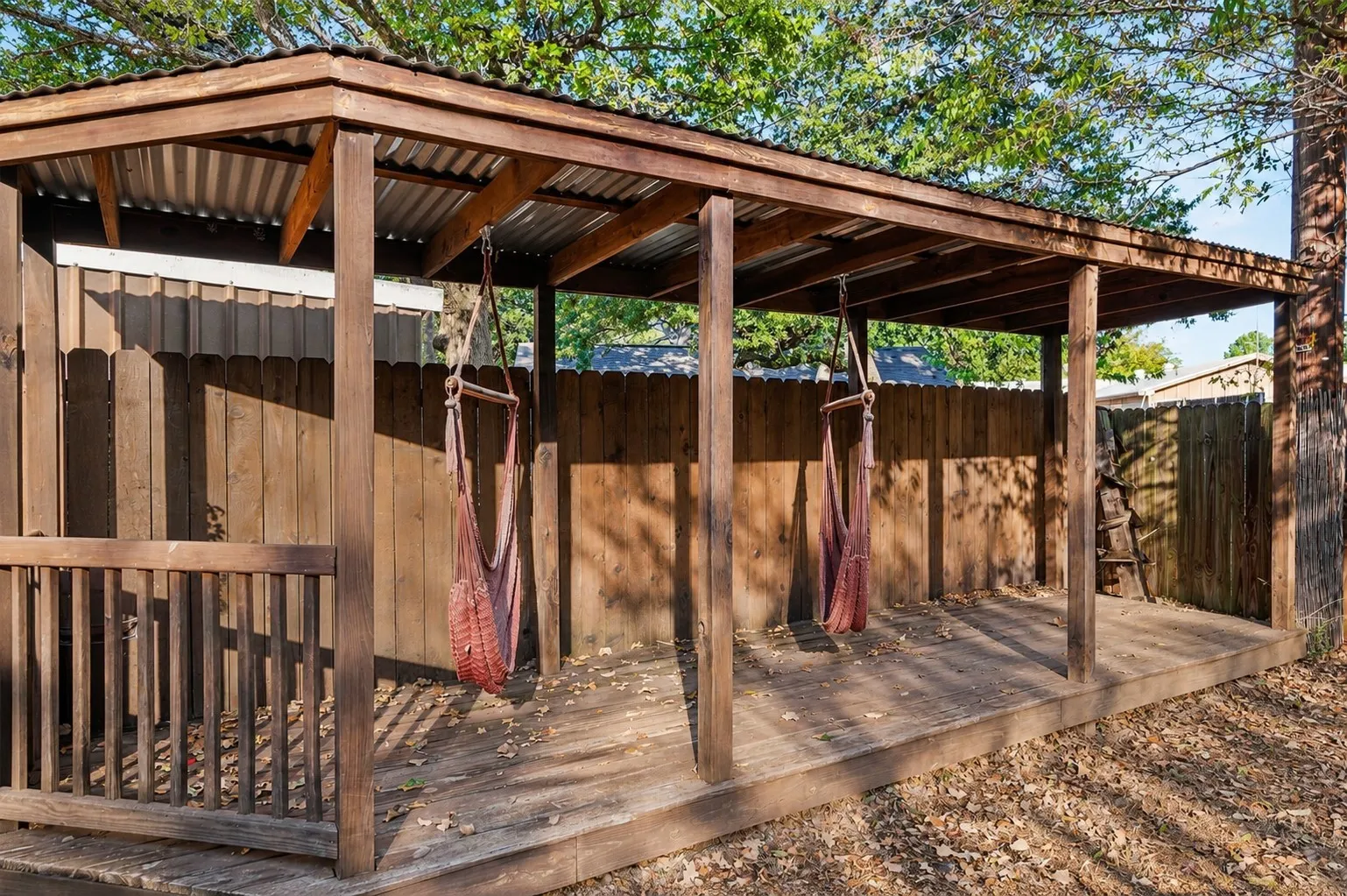 Covered wood deck featuring a corrugated metal roof and wood privacy fencing